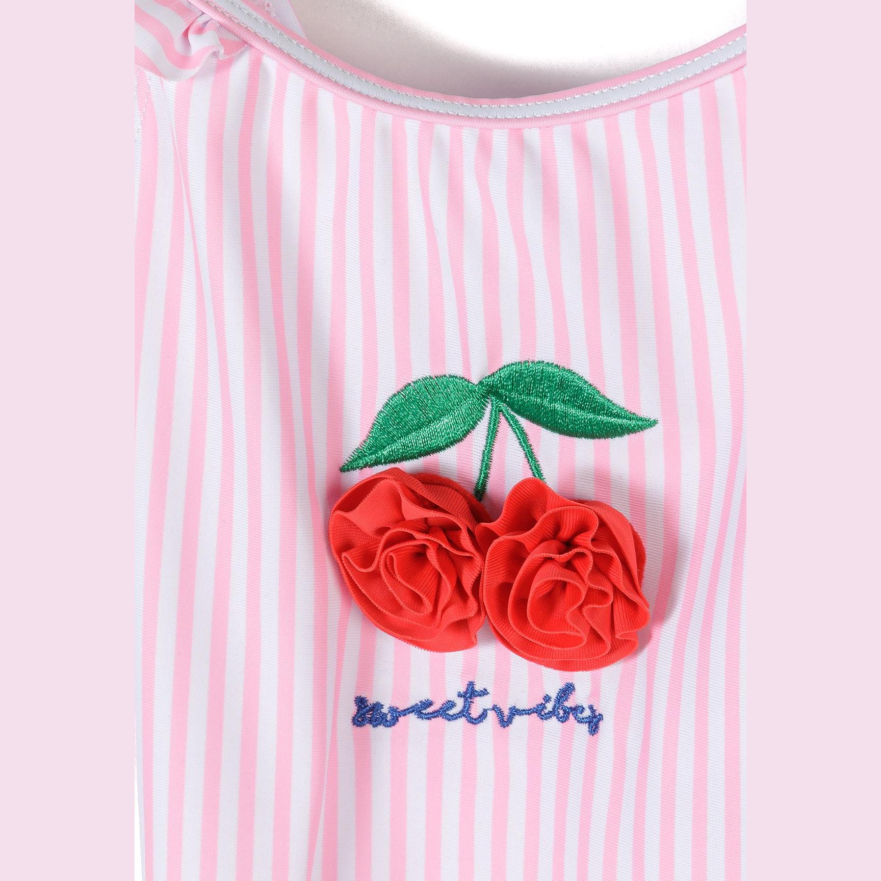 Close-up detail of 3D red cherry appliqué with green leaves and 'sweet vibes' embroidered text on pink striped fabric