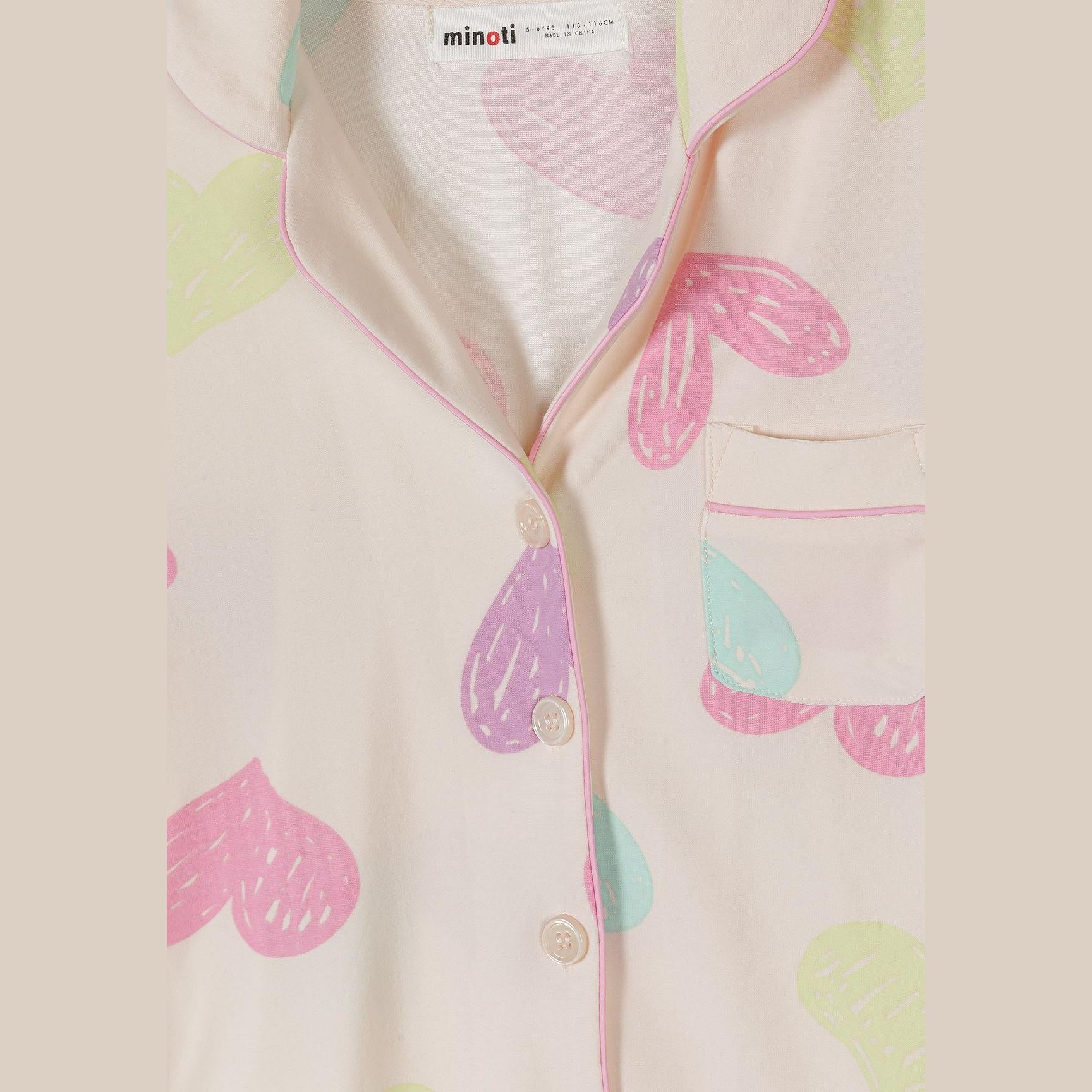 Detail shot of pyjama top showing Minoti label, button closure, heart pattern and chest pocket with pink trim
