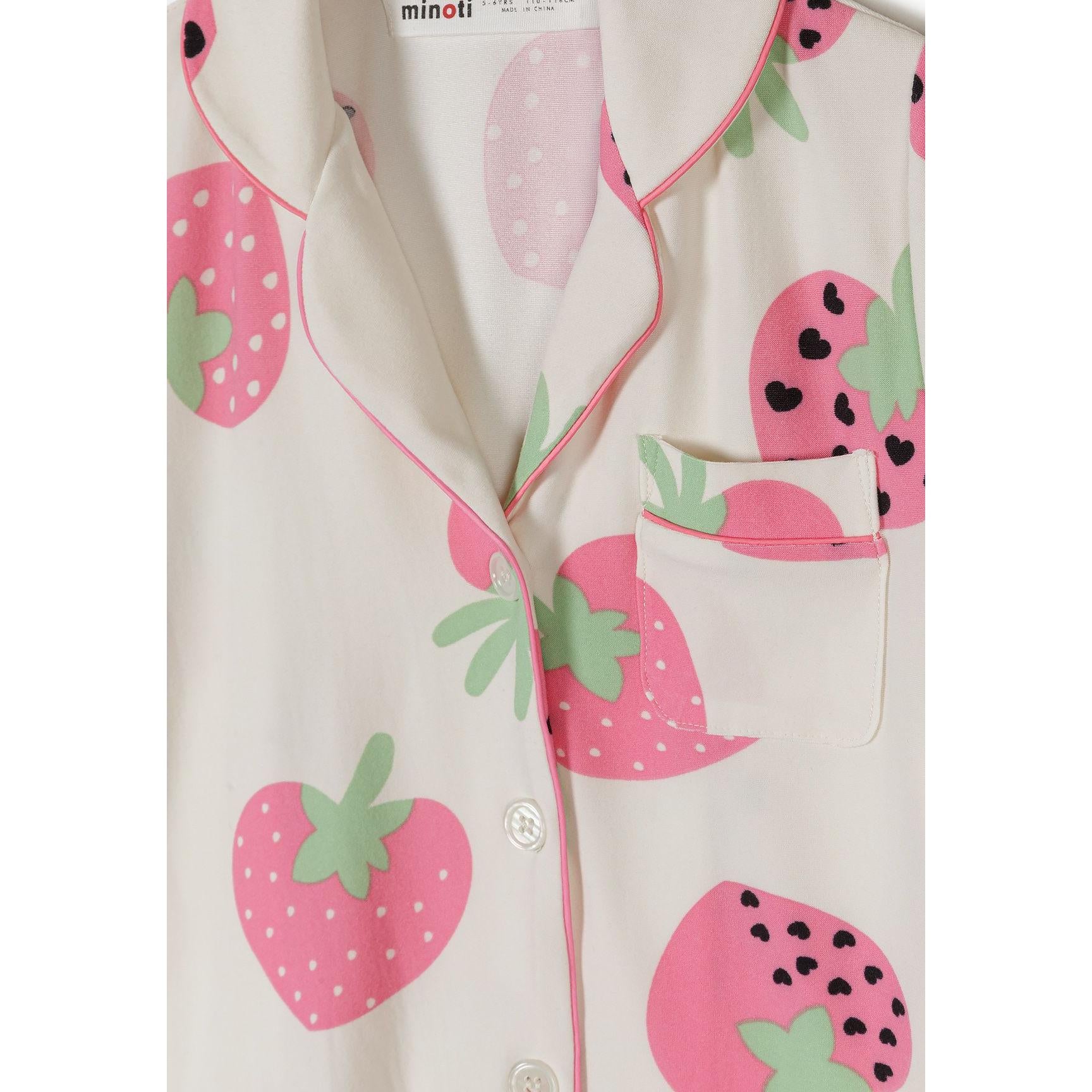 Close-up detail of cream pyjama top showing strawberry print pattern, pink collar trim, chest pocket and button closure with Minoti label visible