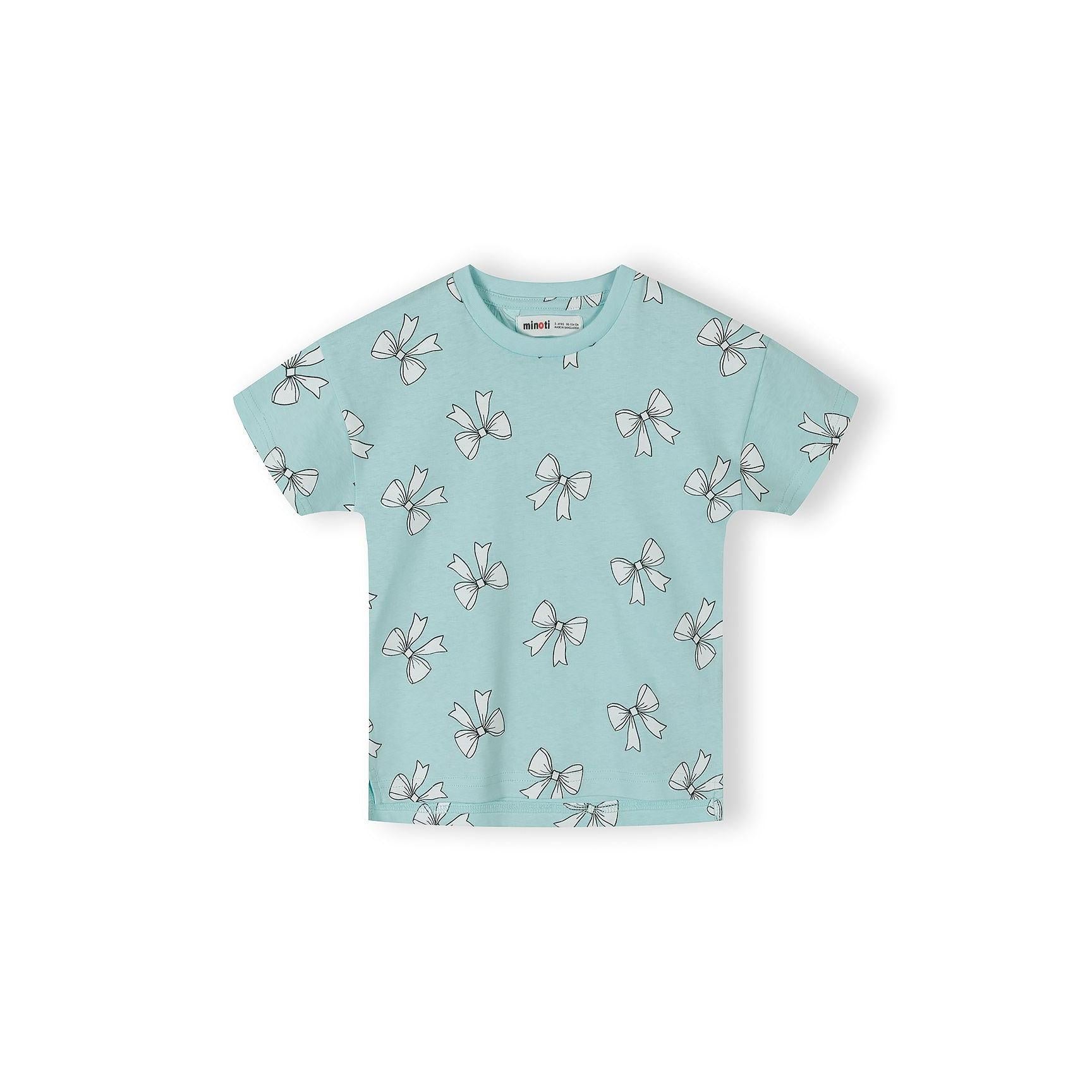 Close-up detail of pink cotton t-shirt fabric showing bow print pattern with blue bows, text elements including 'AWESOME', 'GIRLY', 'COOL' and heart shapes scattered across pink background