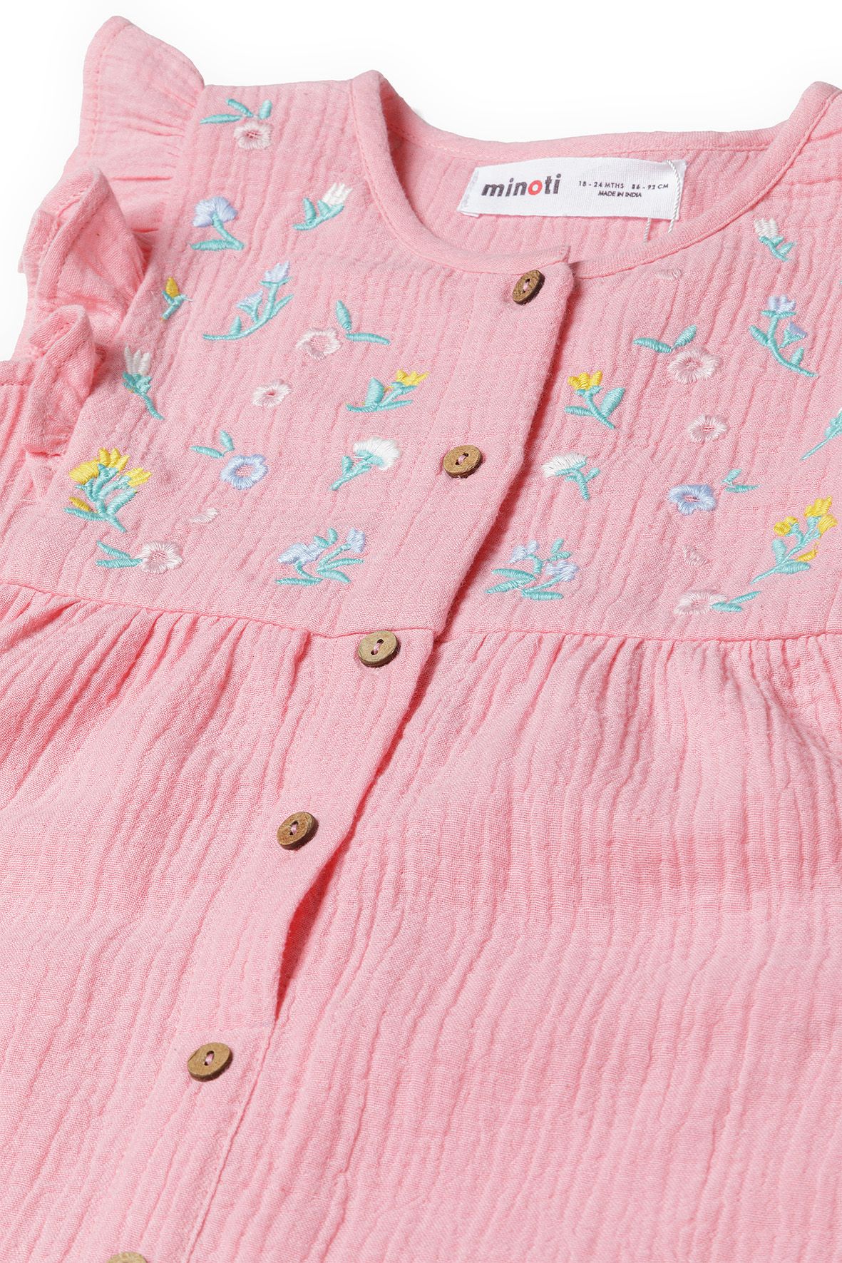 Close-up of pink jumpsuit's floral embroidery and tan front buttons.