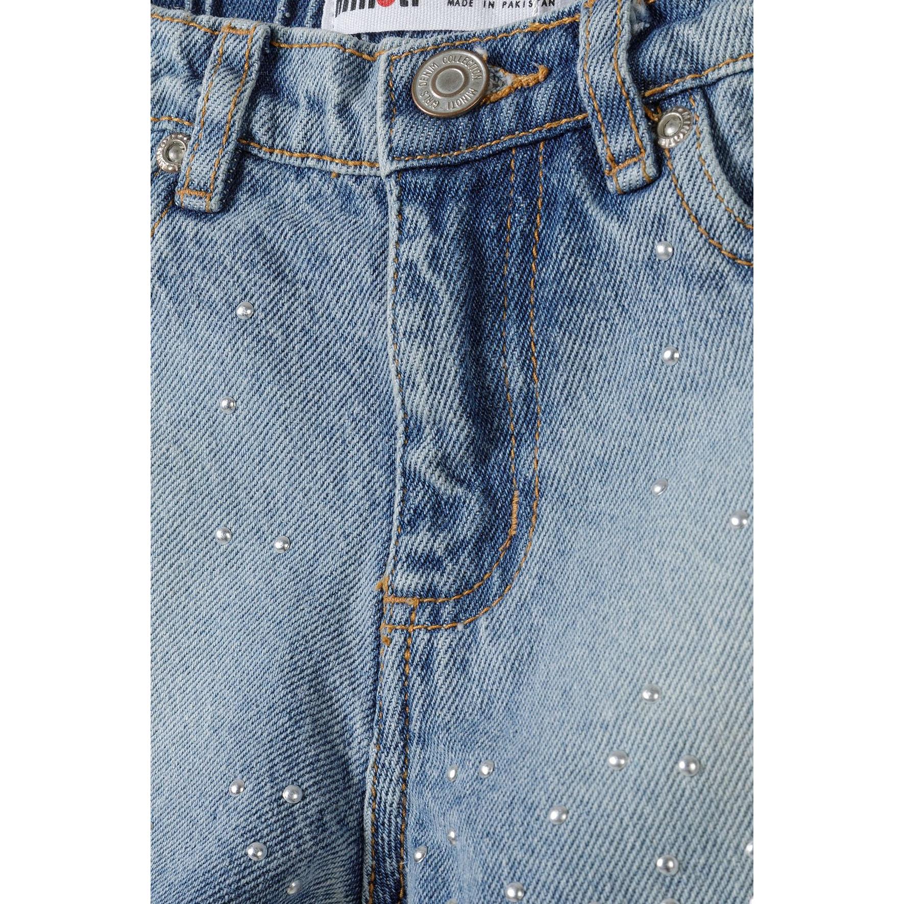 Close-up detail of light blue denim fabric showing white stud detailing and Minoti brand label at waistband with orange contrast stitching