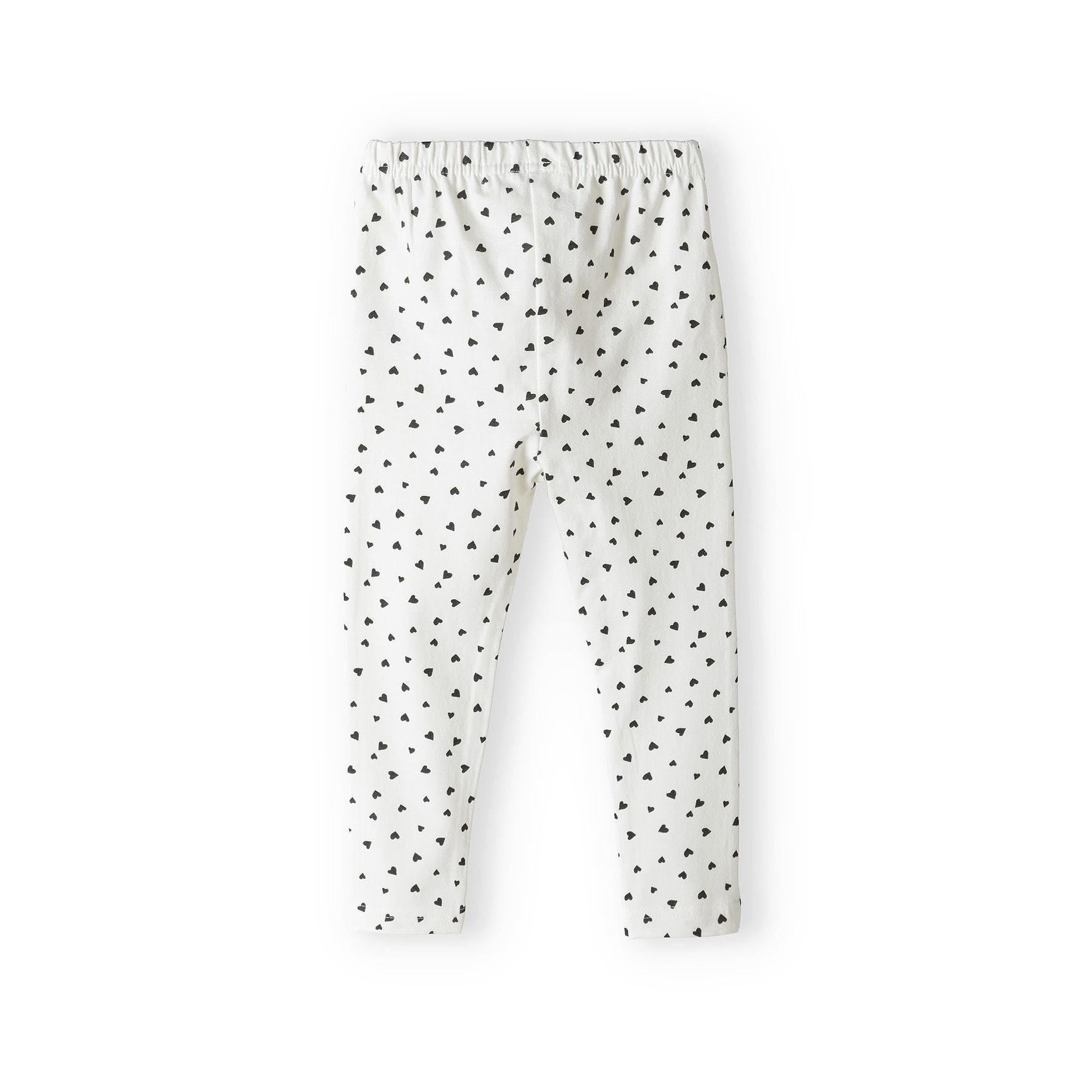 Cream coloured leggings with black heart print pattern all over, laid flat on white background