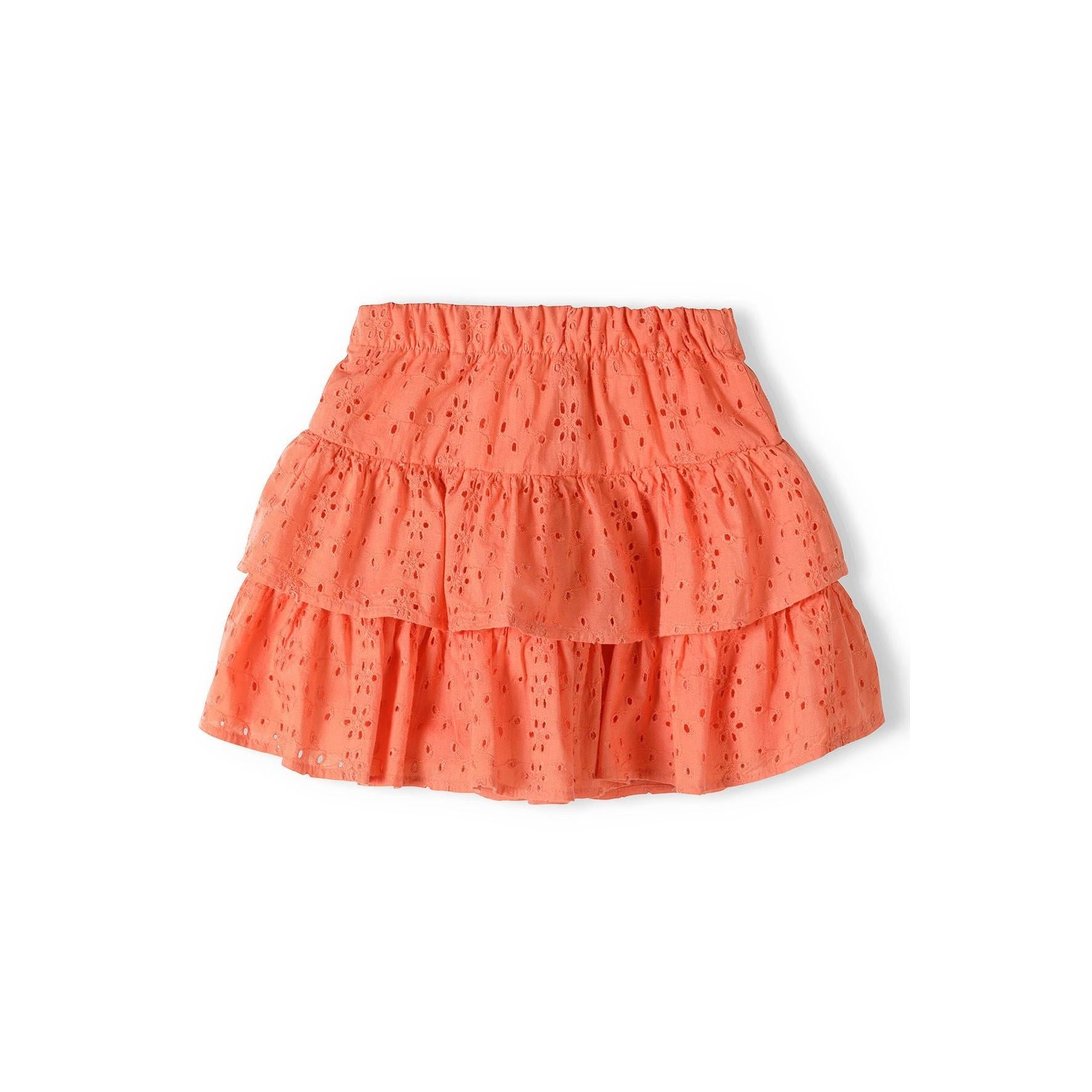Coral broderie anglaise skirt with intricate embroidered holes and two-tier ruffle design laid flat on white background