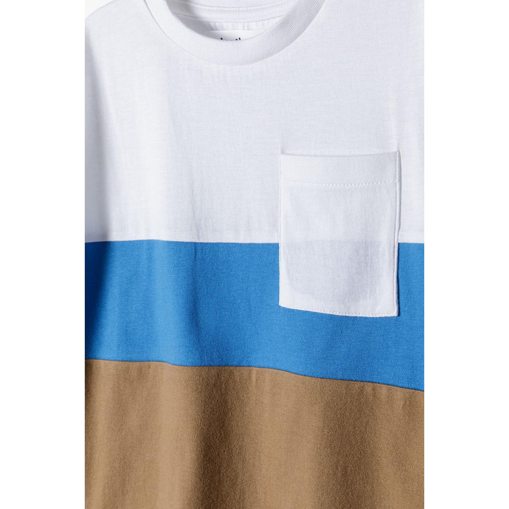 Close-up detail of white chest pocket on t-shirt showing fabric texture and colour-block design transition from white to blue to brown