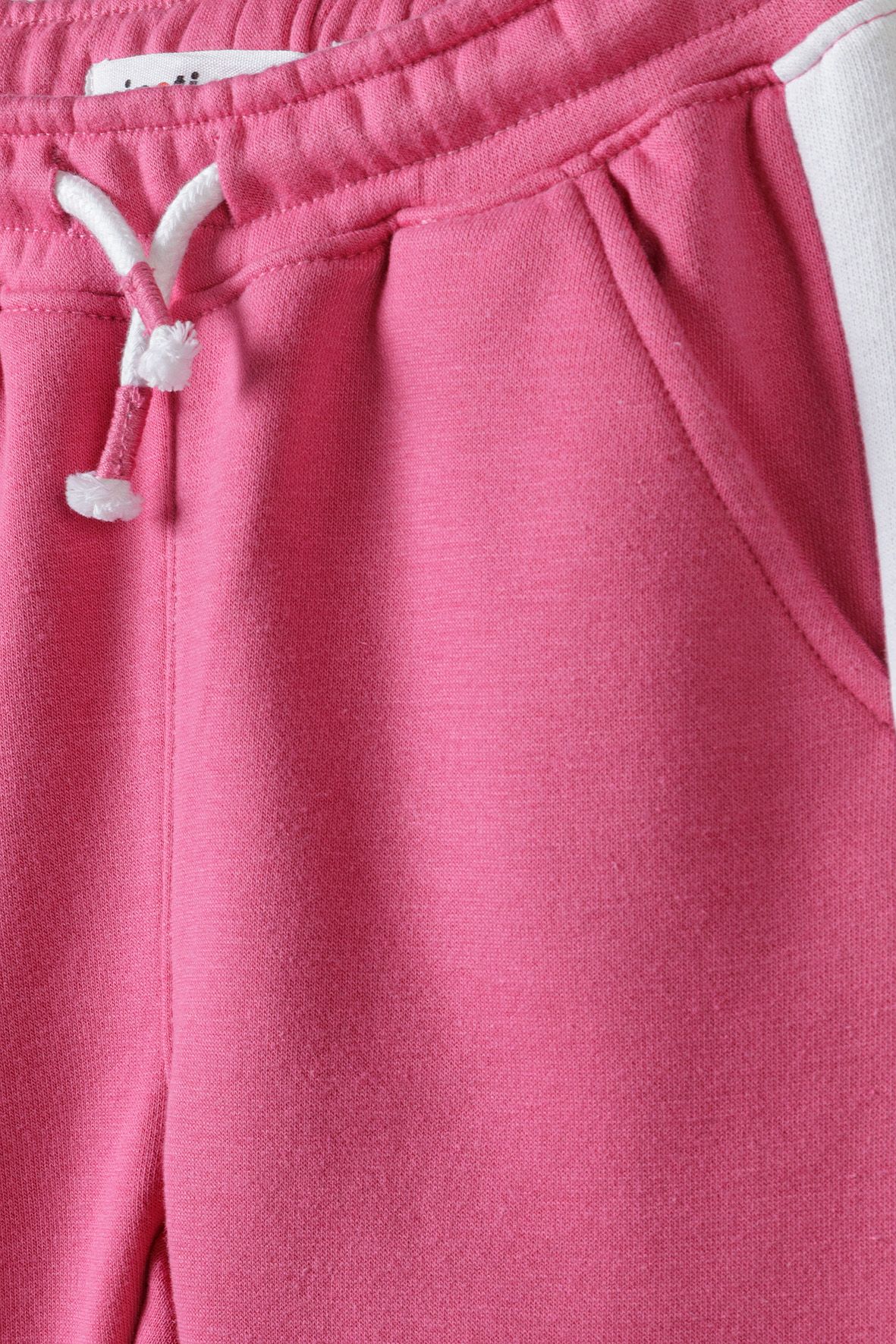 Close-up of pink joggers' white drawcord, hip pocket and side stripe.