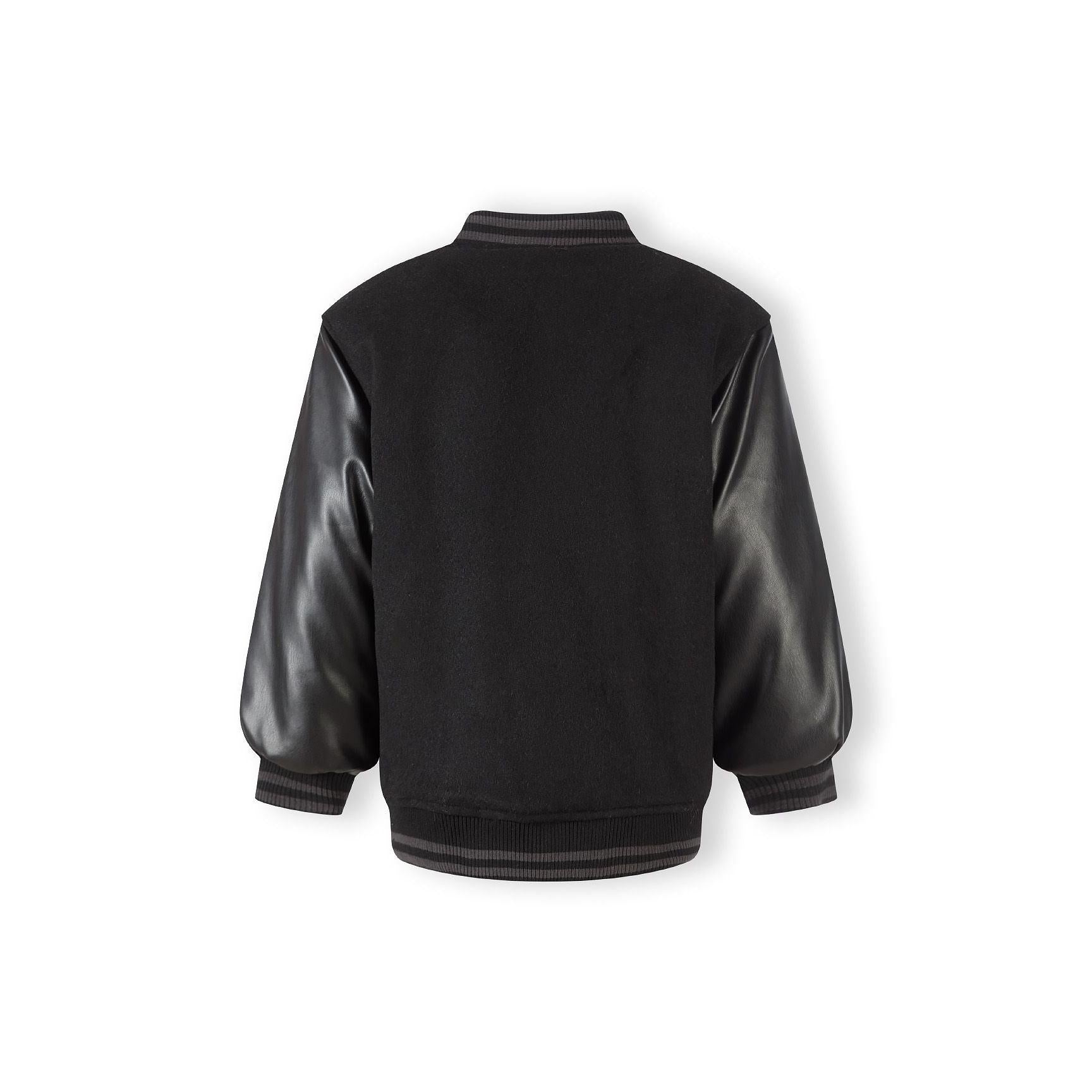 Close-up detail of appliqué M logo in grey and blue with text, showing press stud fastening and black felt fabric texture