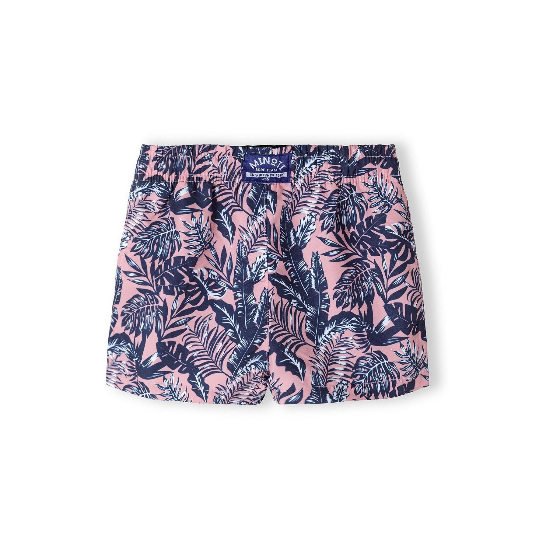Flat lay view of coral board shorts with navy tropical leaf print showing Minoti waistband label and drawstring detail