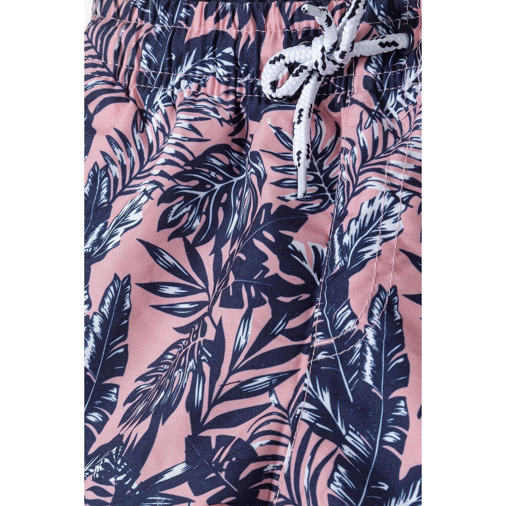 Close-up detail of coral board shorts waistband showing elasticated band with white drawstring and tropical leaf print fabric texture