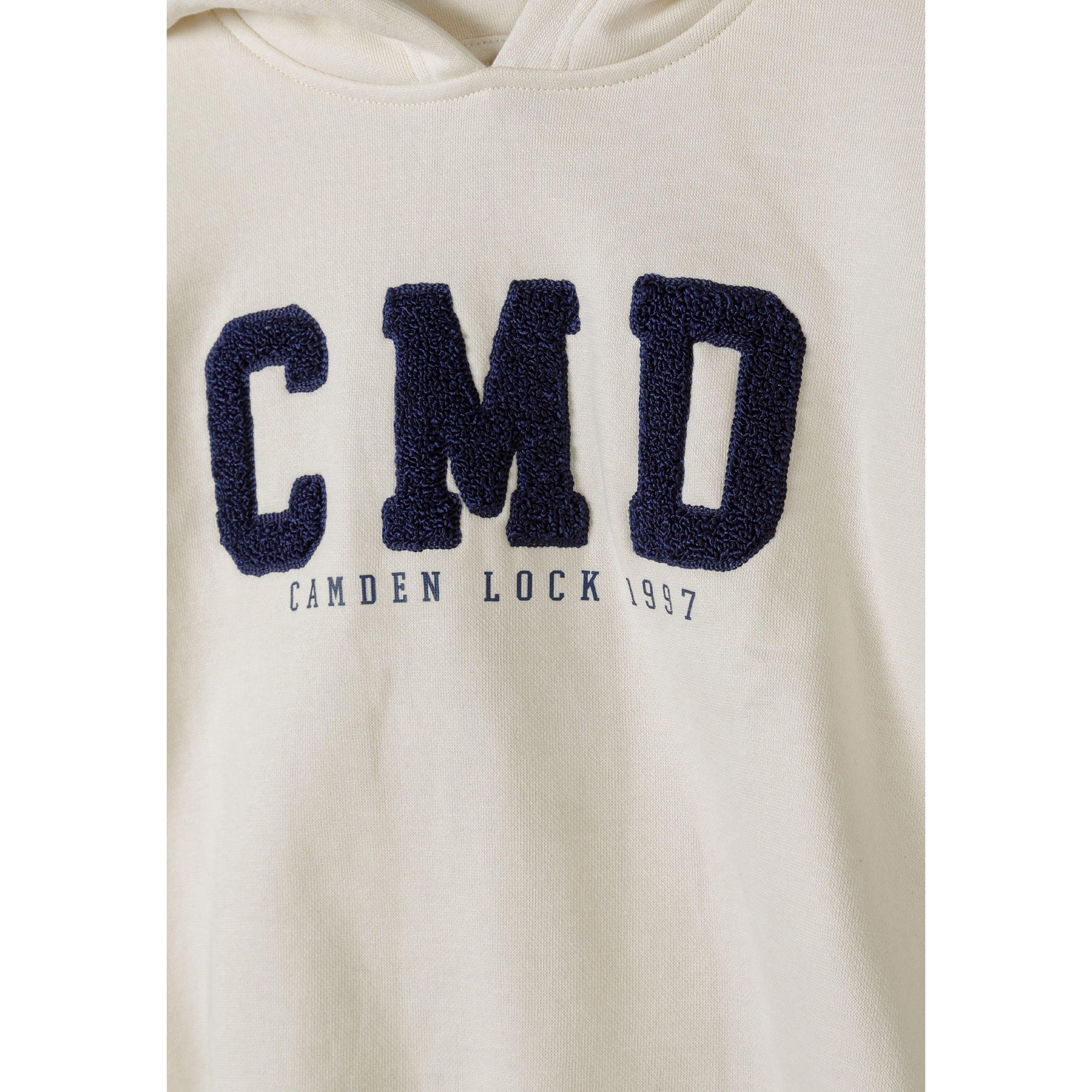 Close-up detail of cream joggers showing large navy blue C boucle embroidery and drawstring waistband