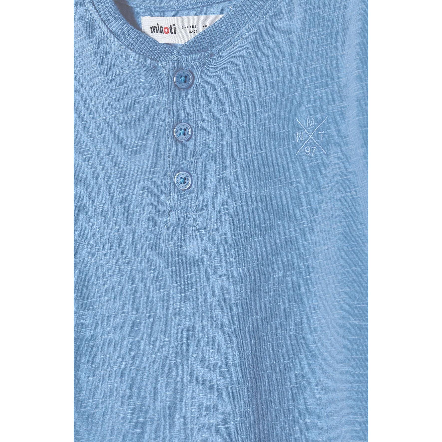 Close-up detail of blue henley t-shirt showing Minoti label and three-button placket with small logo embroidery
