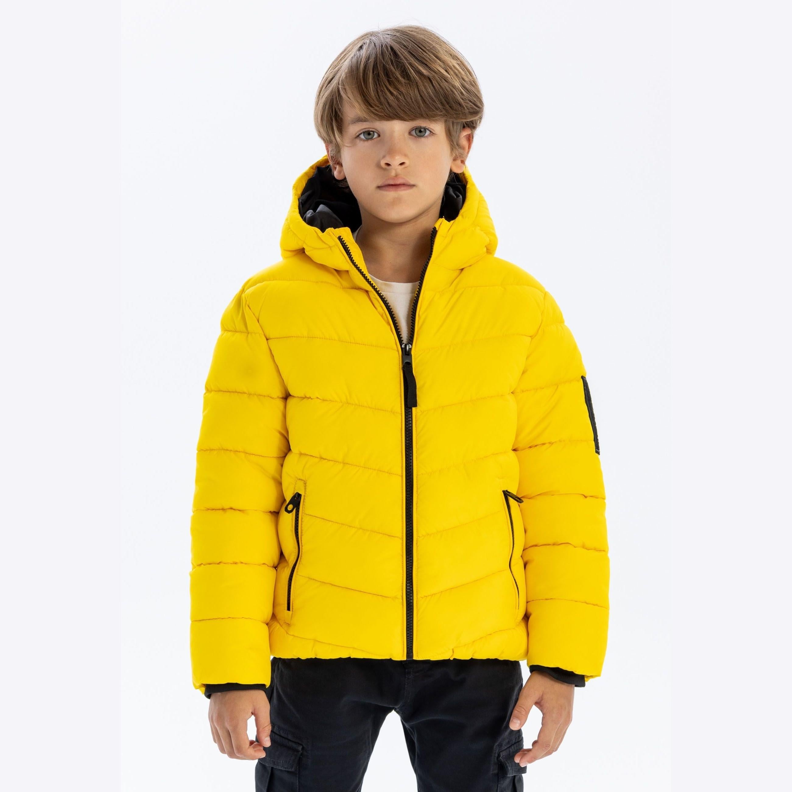 Front view of boy in bright yellow padded winter jacket with hood up, showing full zip closure and ribbed cuffs against light background
