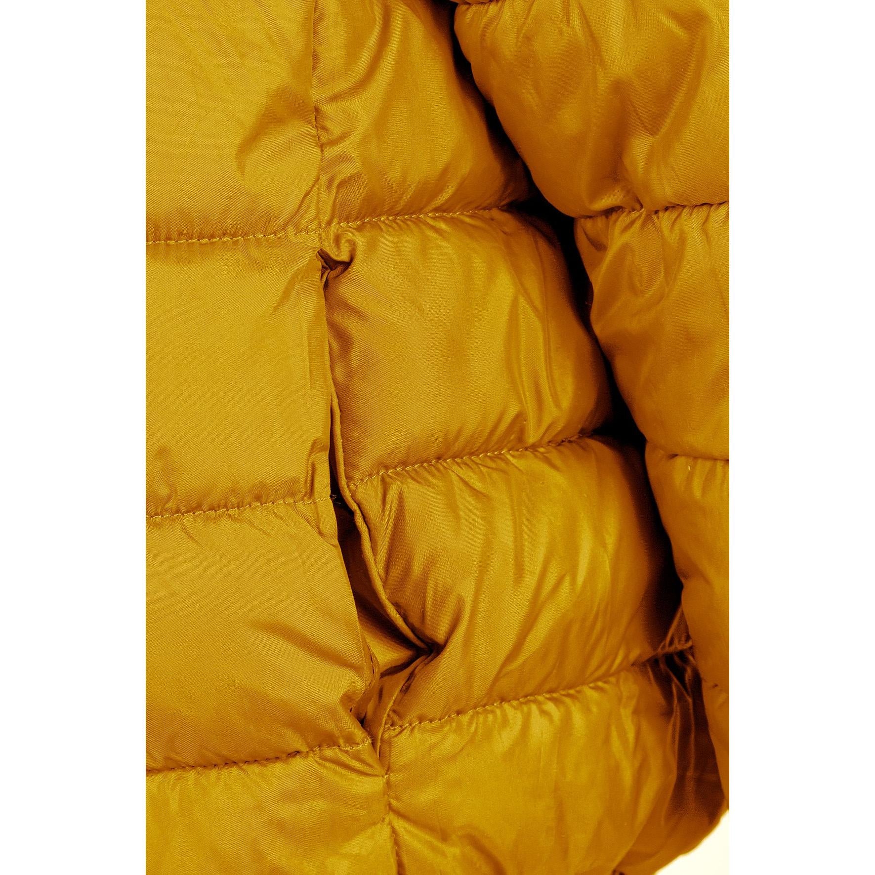 Close-up detail of yellow padded jacket showing horizontal quilted sections and fabric texture with stitching detail