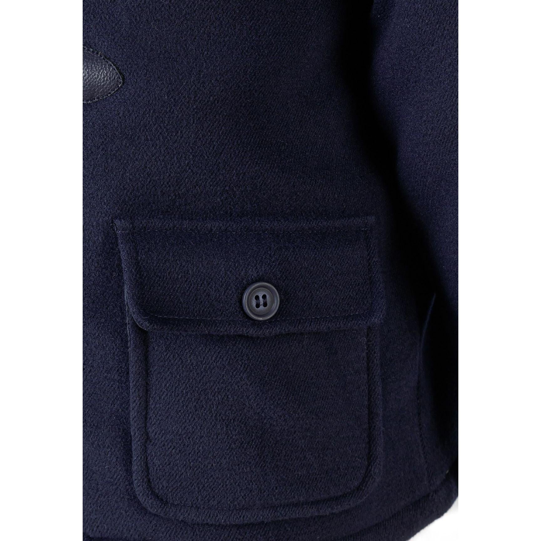Close-up detail of navy fabric showing patch pocket with button closure and textured material