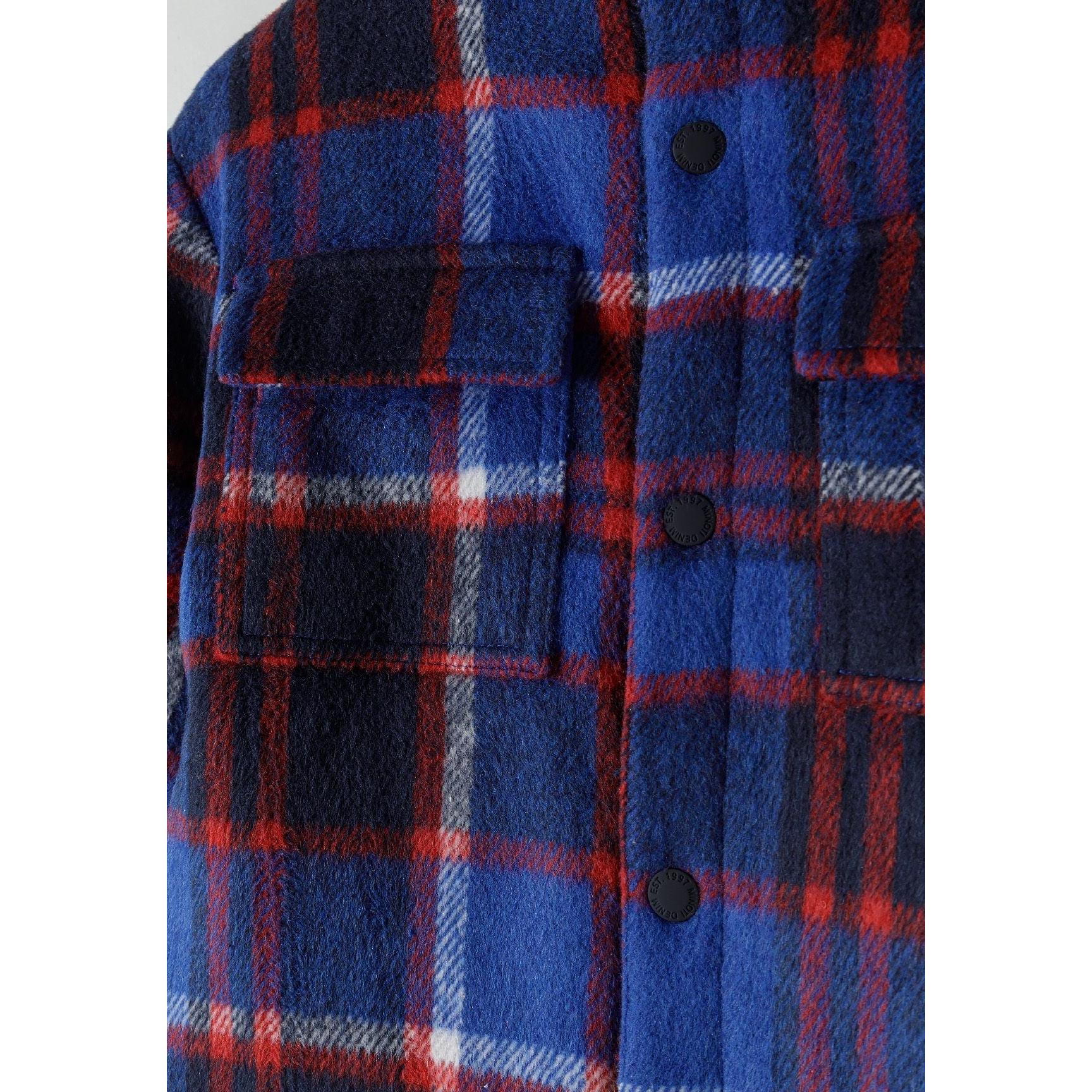 Close-up detail of blue check fabric pattern with black quilted lining visible through open front closure