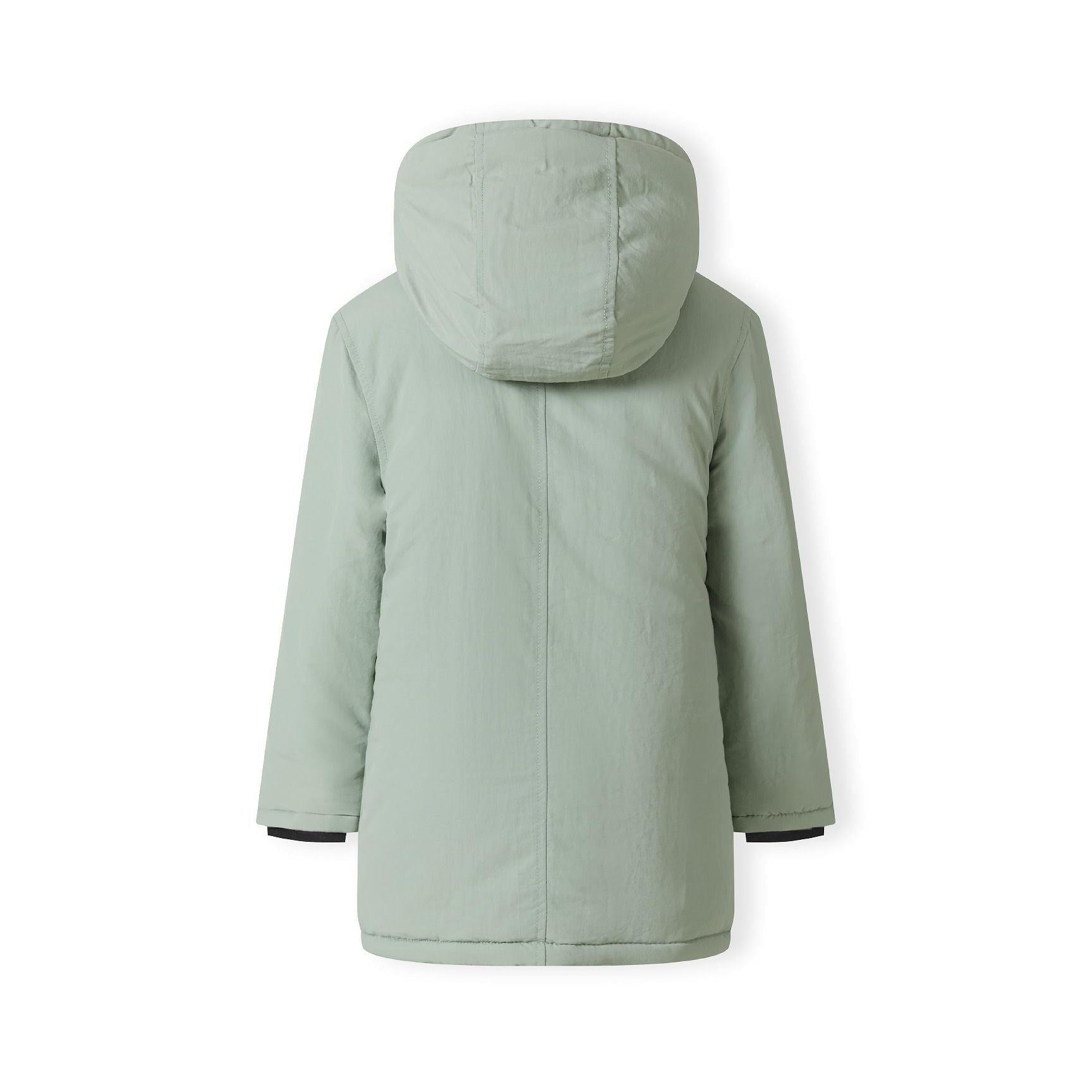 Close-up detail of black circular badge with crossed design on sage green fabric of parka jacket