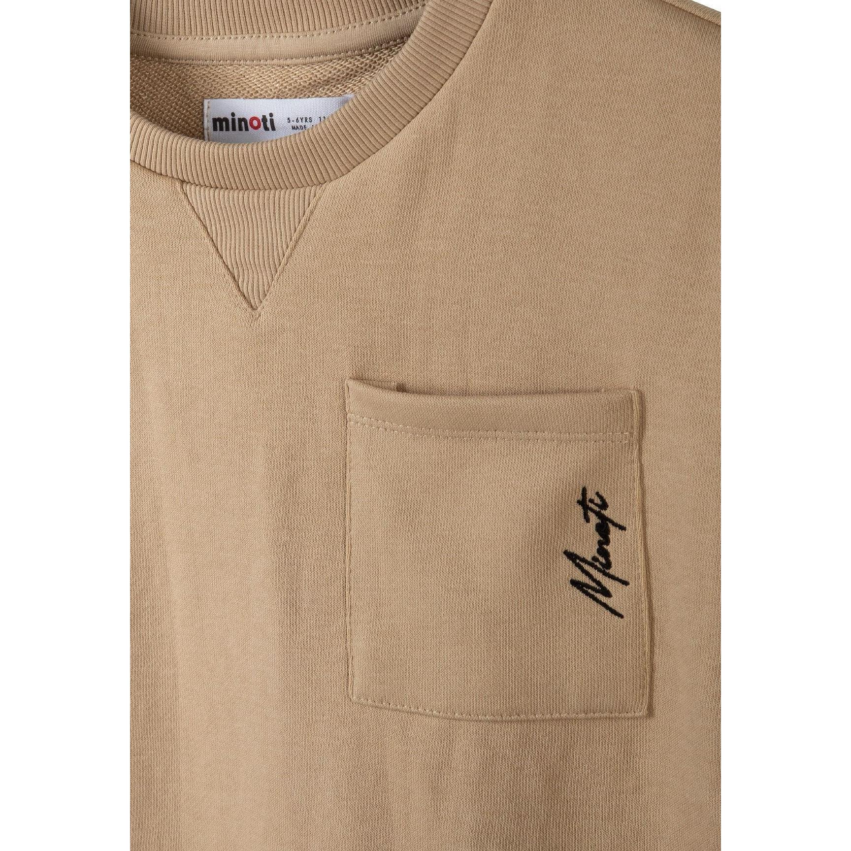Close-up detail of beige cotton shorts showing elasticated waistband with black drawstring and Minoti label
