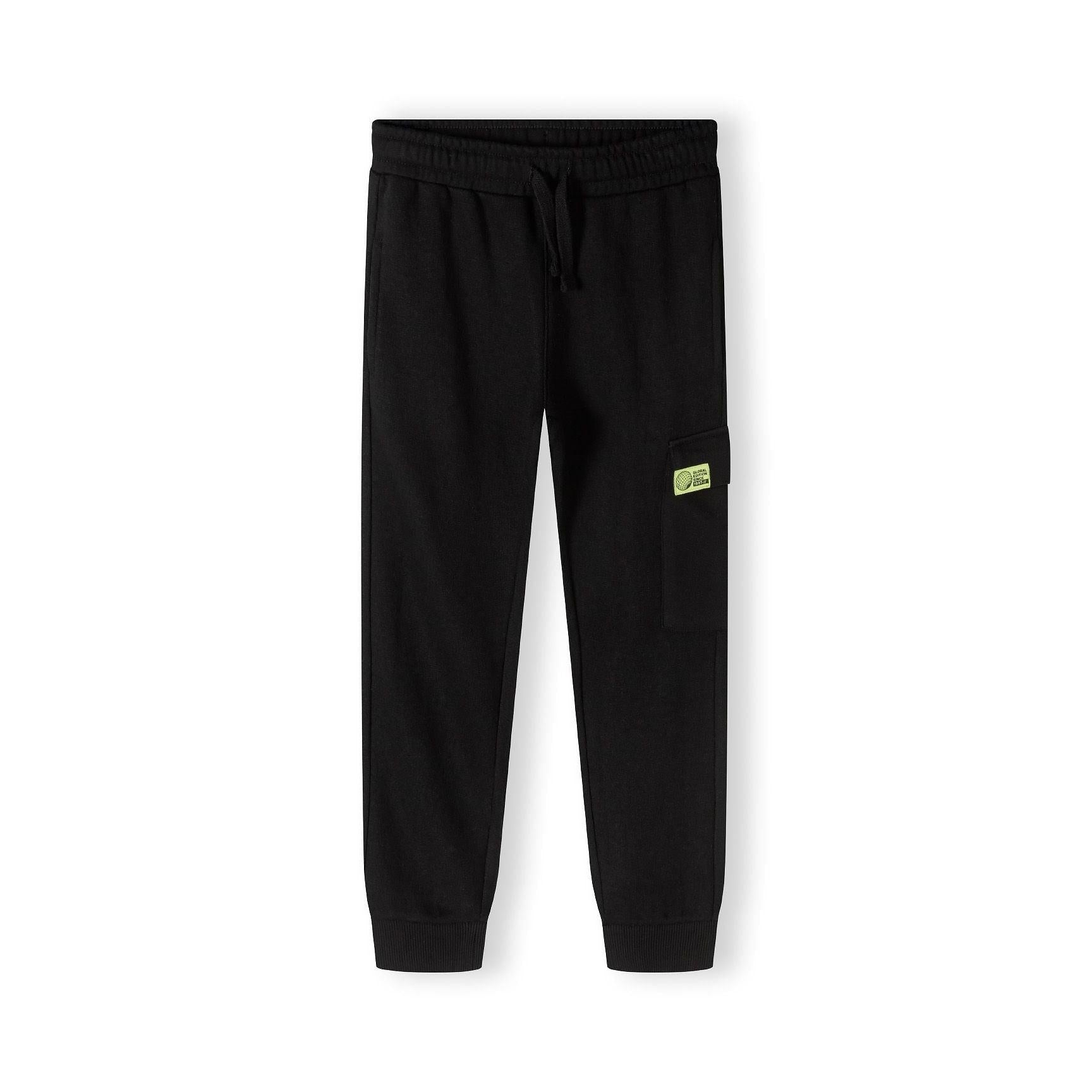 Close up detail of black fleece joggers showing drawstring waistband and green label patch