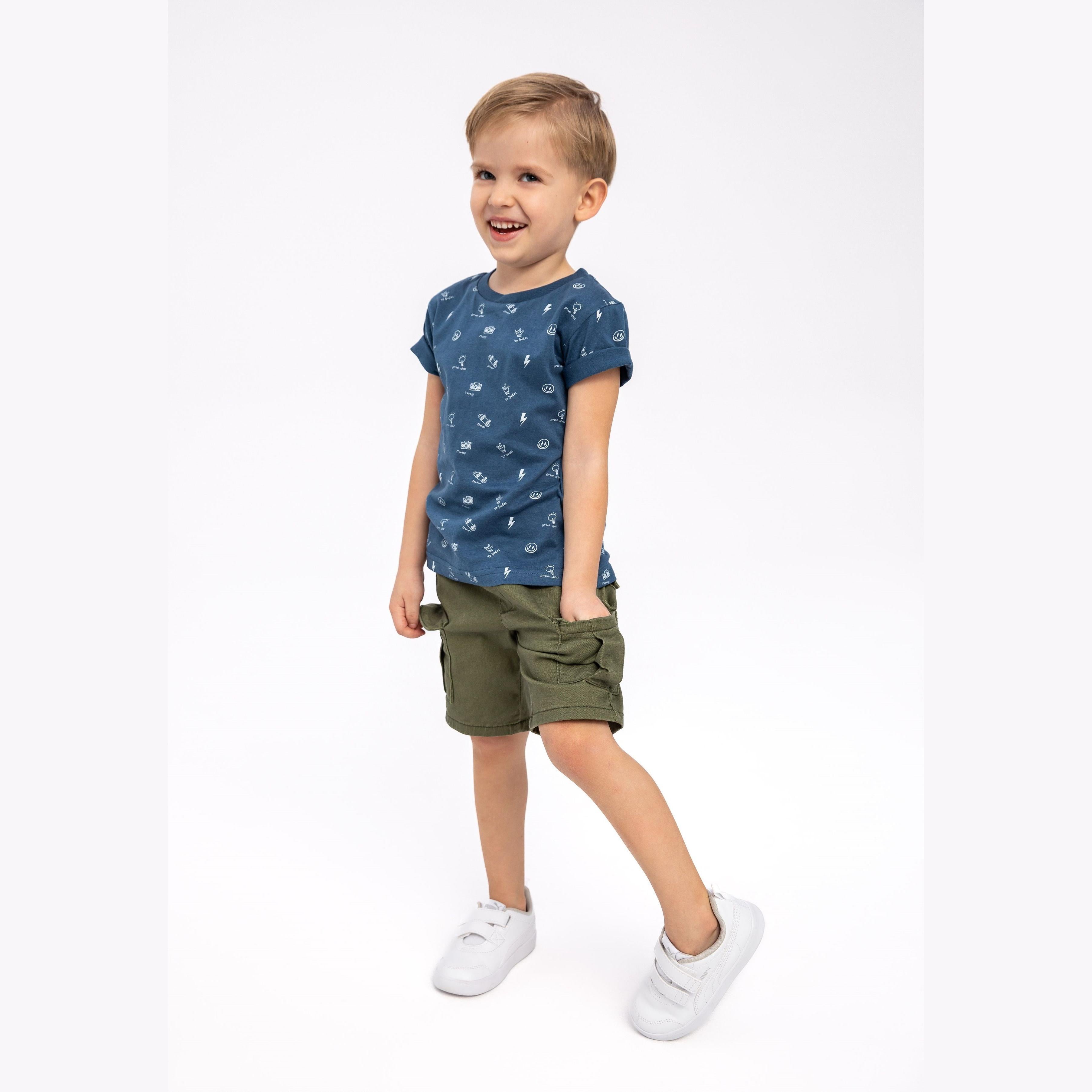 Young boy wearing navy t-shirt with small graphics and khaki shorts, smiling against white background