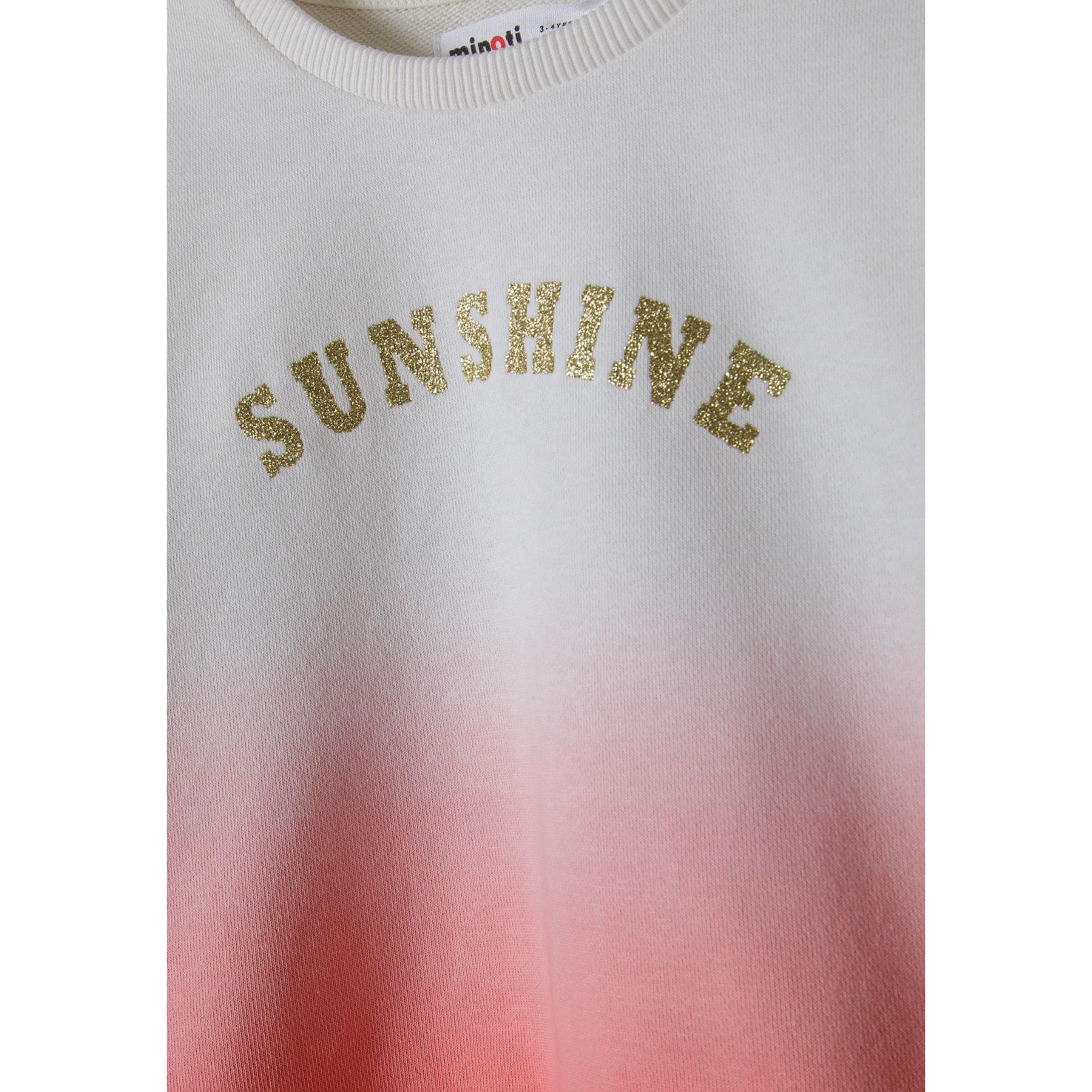Close-up detail of sparkly gold SUNSHINE lettering on coral gradient fleece sweatshirt showing texture and Minoti label
