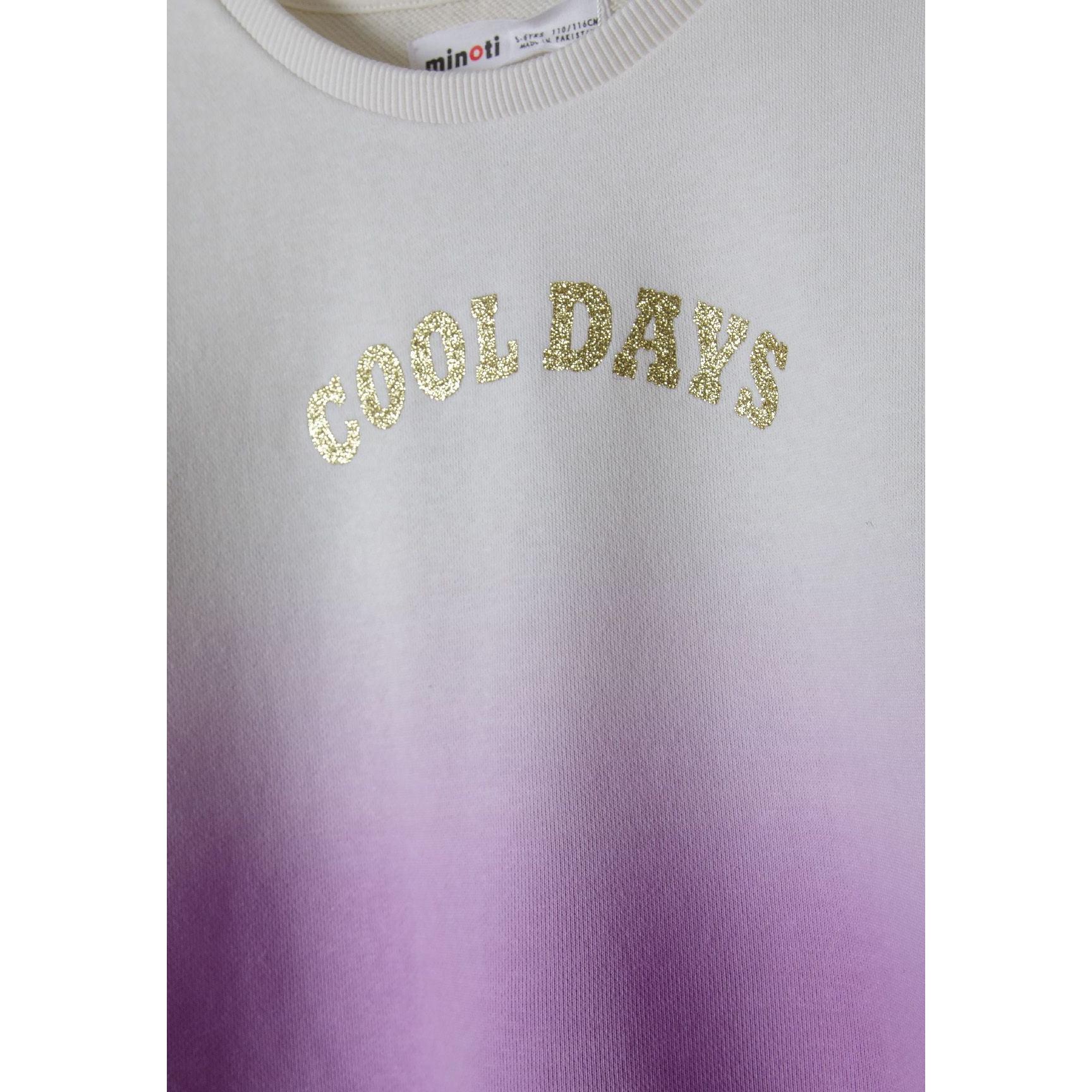 Close-up detail of cream to purple ombré fleece fabric with golden glitter 'Cool Days' text and Minoti brand label