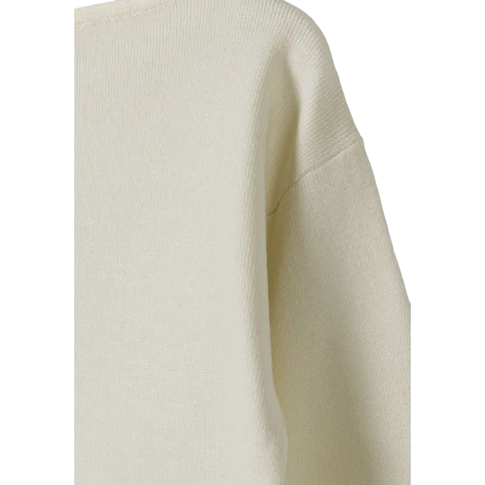 Close-up detail of cream textured knit jumper showing soft fabric texture and seam construction against black background