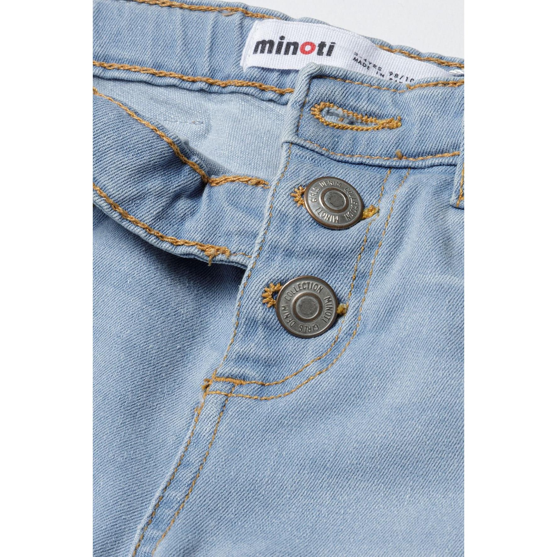 Close-up detail of light blue denim showing Minoti label, silver button closure and orange contrast stitching