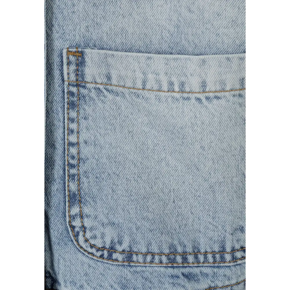 Close-up detail of light blue denim jacket chest pocket showing acid wash texture, contrast stitching and classic pocket construction