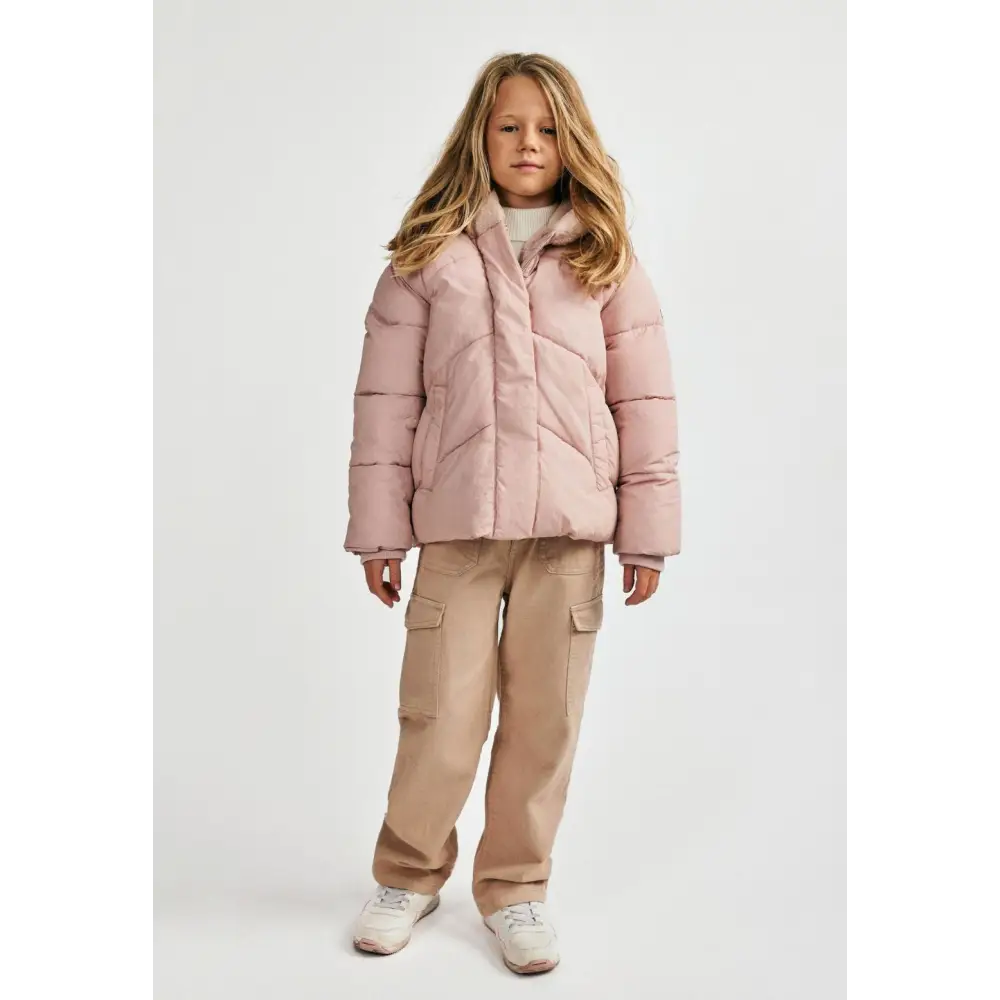Girl wearing pink padded jacket with beige cargo trousers and white trainers, full body front view on white background