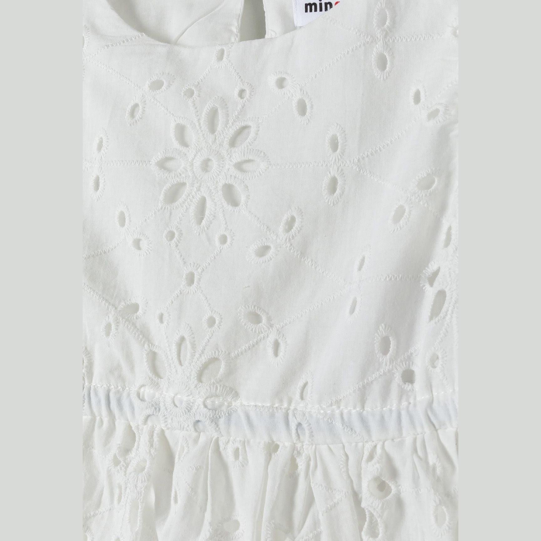 Close-up detail of white broderie anglaise embroidery showing intricate floral cutwork patterns