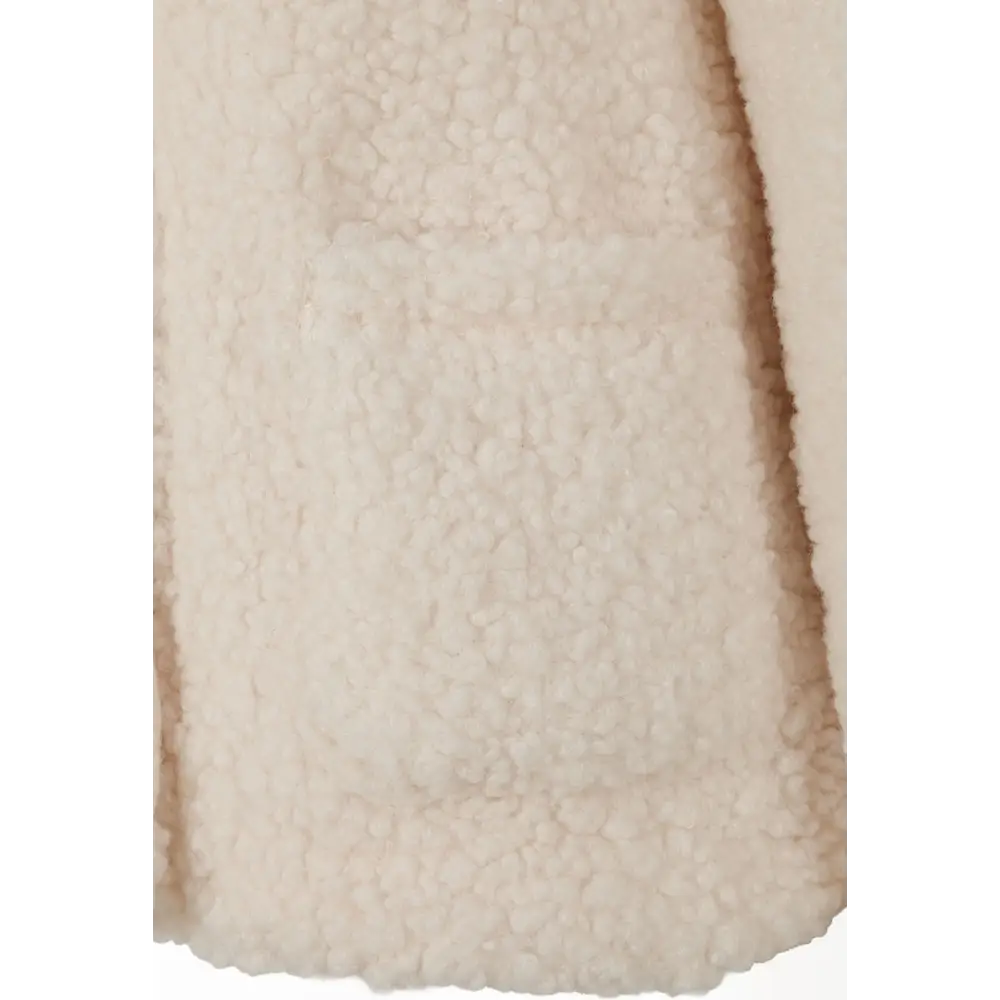 Close-up detail of cream teddy fleece fabric texture showing soft plush finish