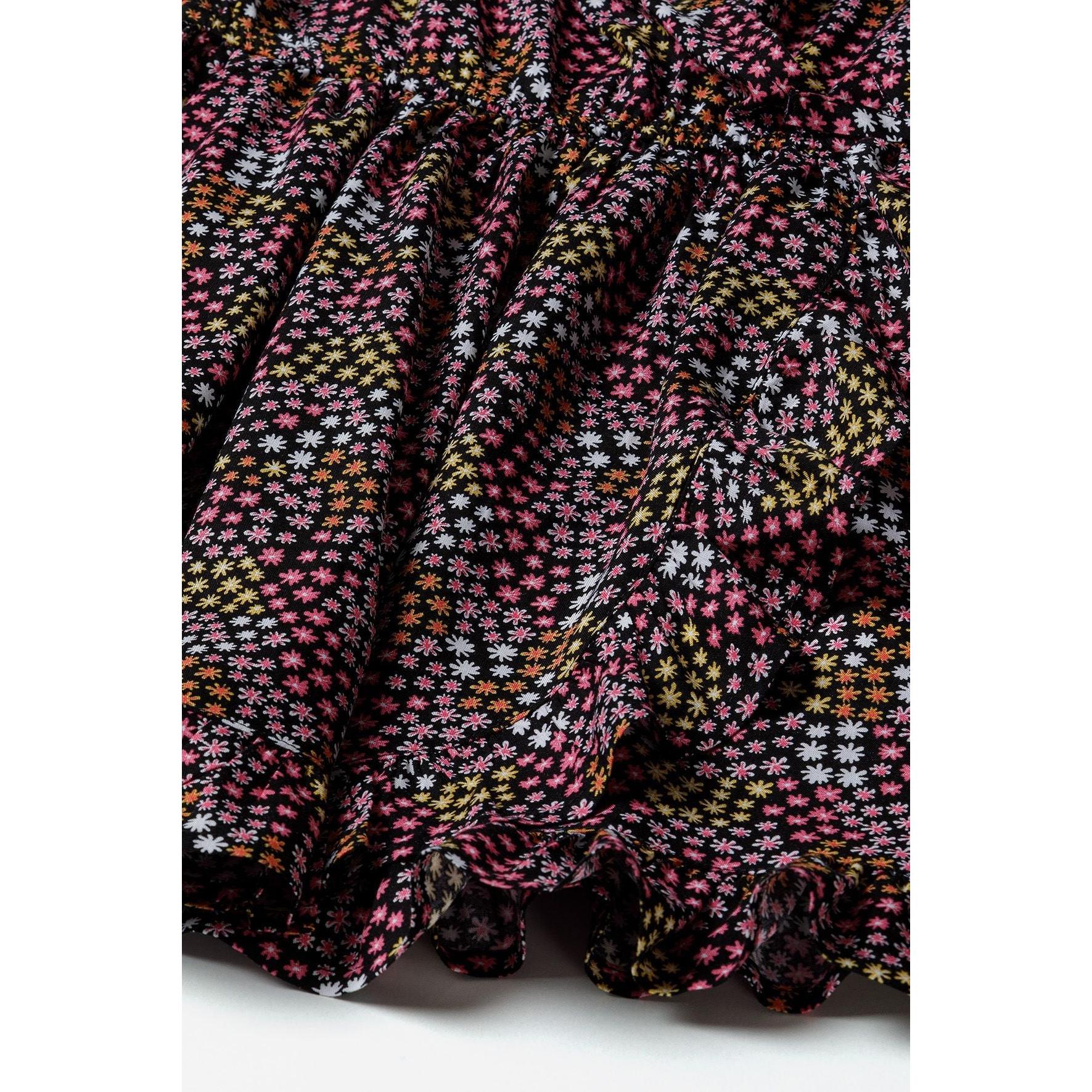 Close-up detail of multicoloured star print fabric showing pink, orange, yellow and white stars on black background with gathered textile texture
