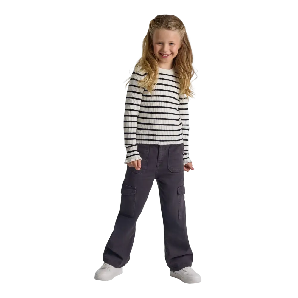 Young girl wearing grey wide leg cargo trousers with black and white striped ribbed sweater, full body studio shot on black background