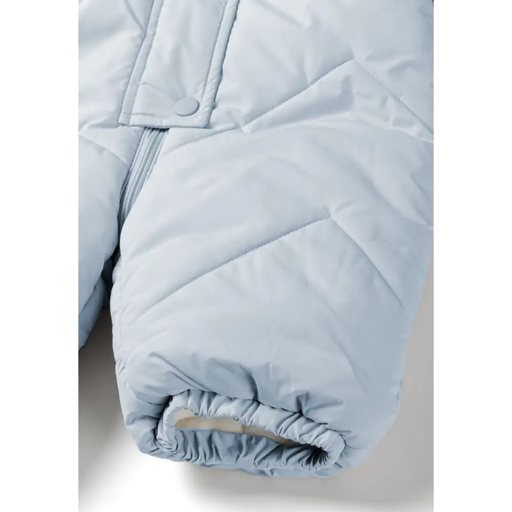 Close-up detail of light blue snowsuit sleeve showing quilted texture, elasticated cuff with gathered fabric on white background