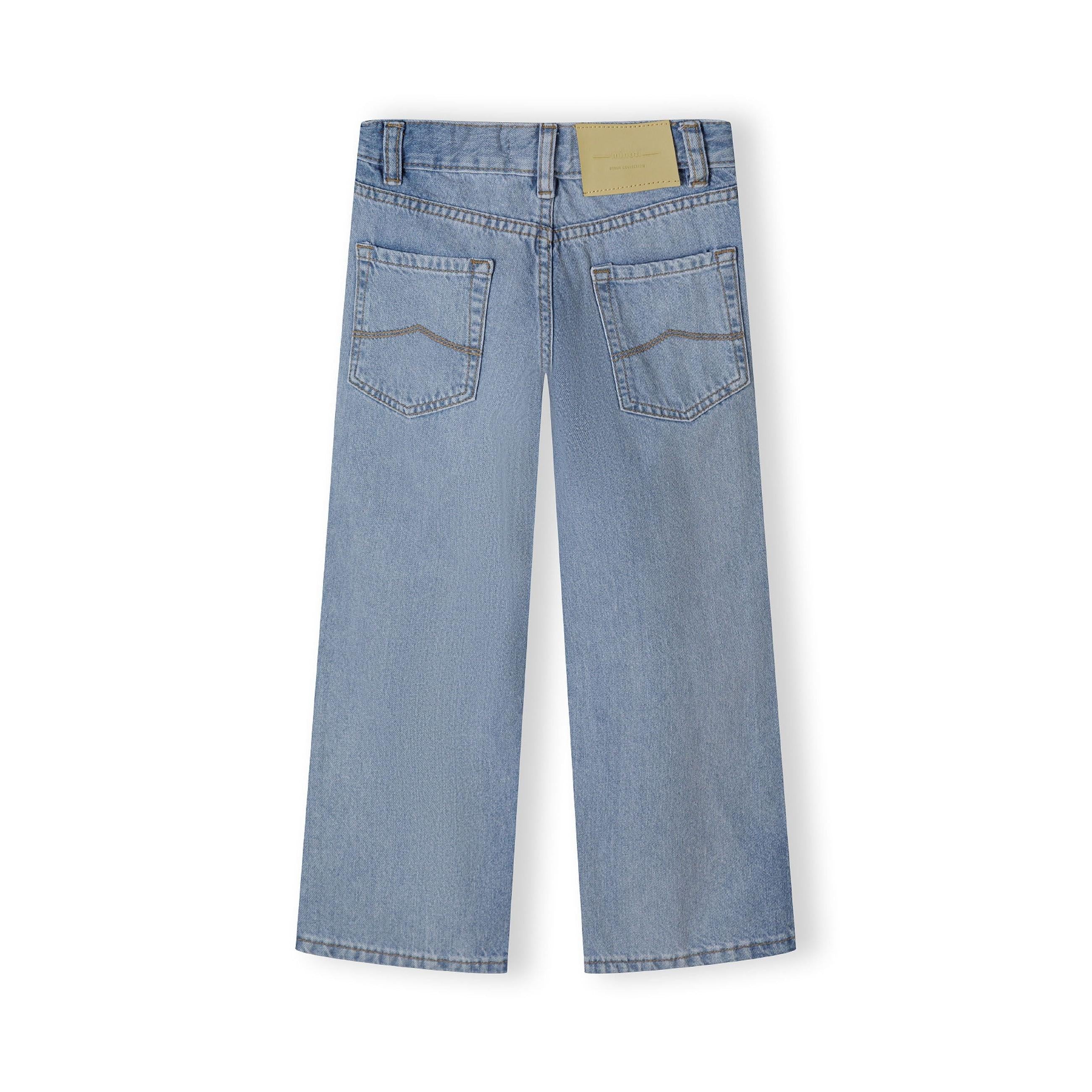 Back view of light blue baggy fit jeans laid flat showing five-pocket design, waistband details and beige leather patch label