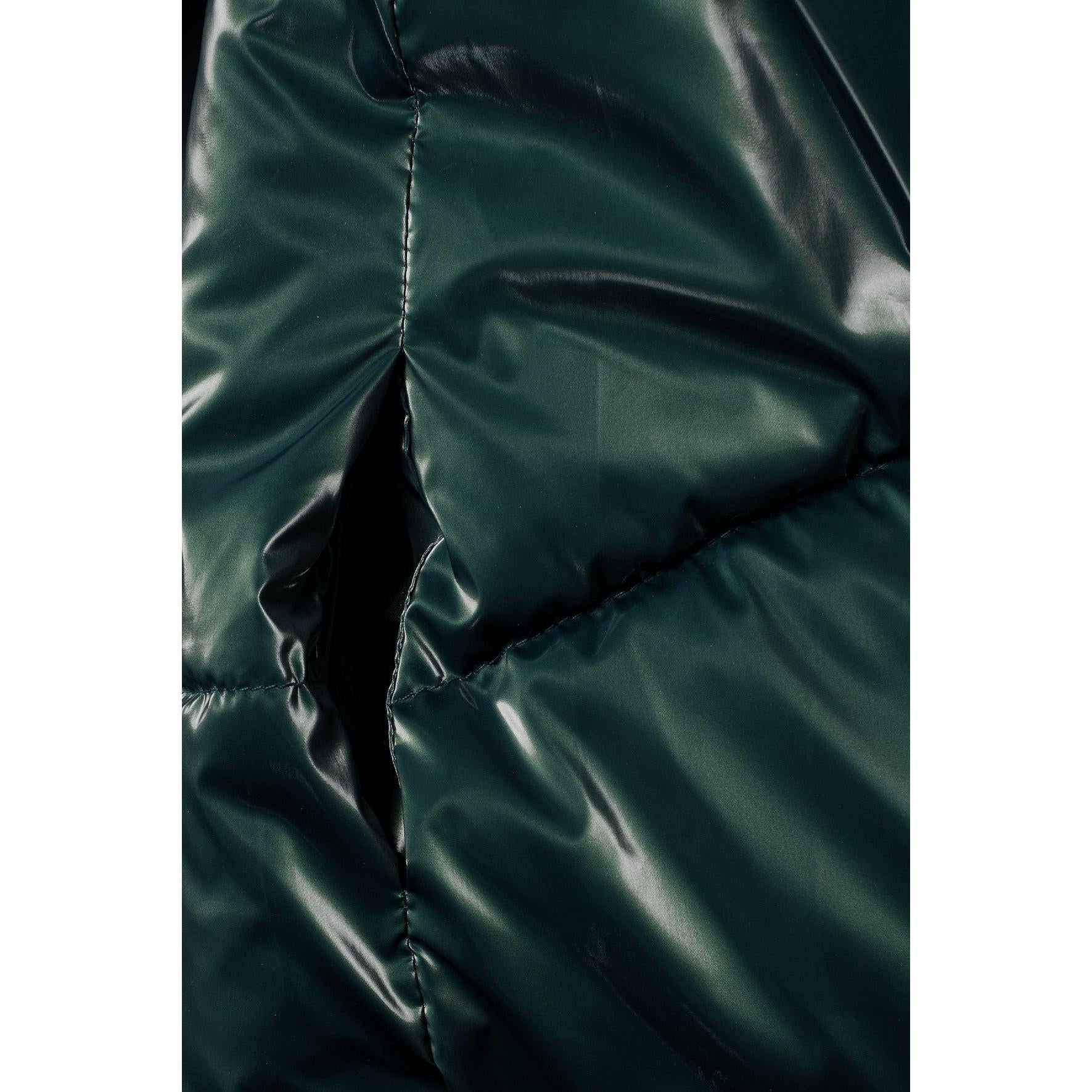 Close-up detail of metallic dark green fabric texture showing quilted padding and shiny finish