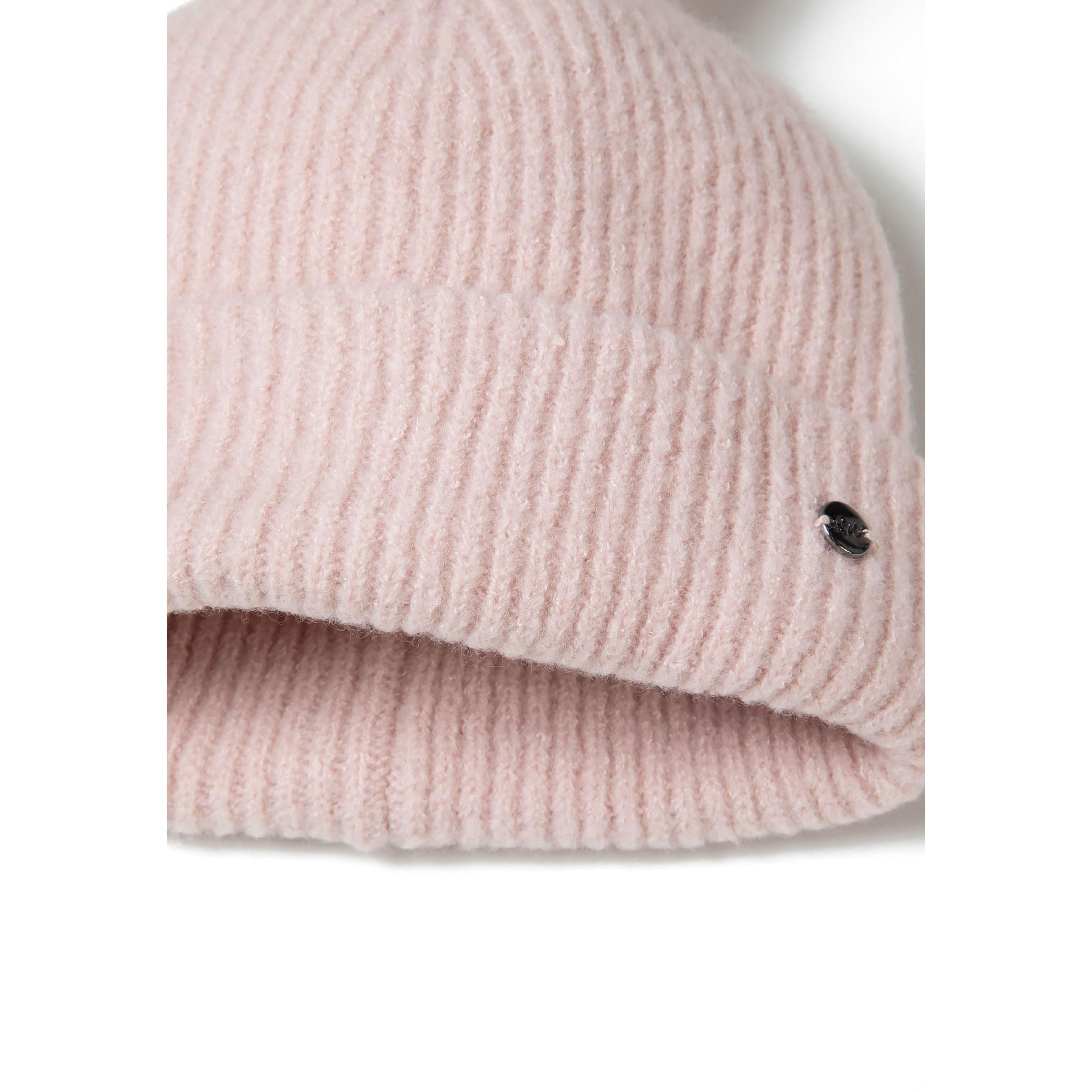 Close-up detail of pale pink ribbed knit fabric texture showing round metal Minoti brand badge