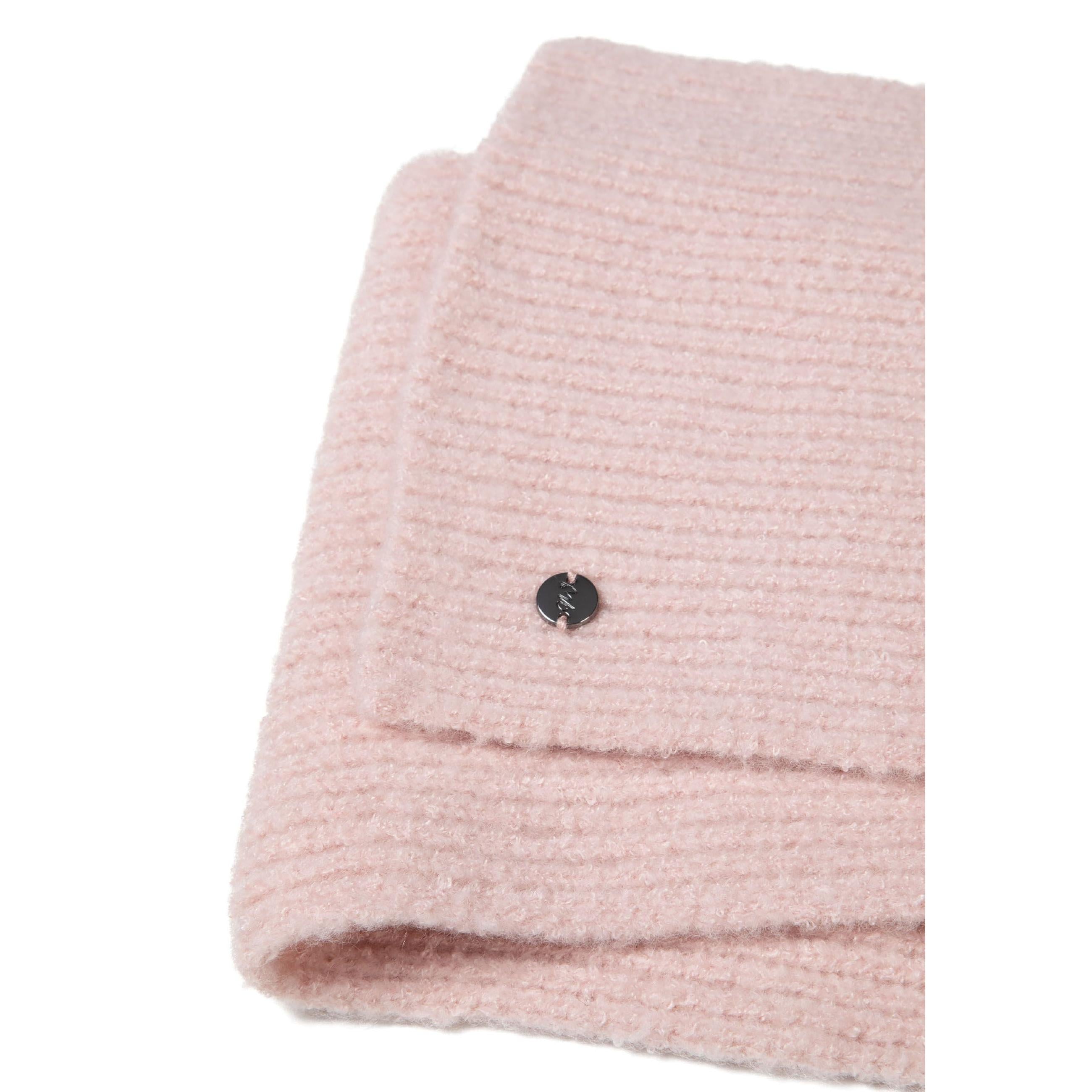 Close-up detail of pale pink ribbed knit fabric texture showing round metal Minoti brand badge