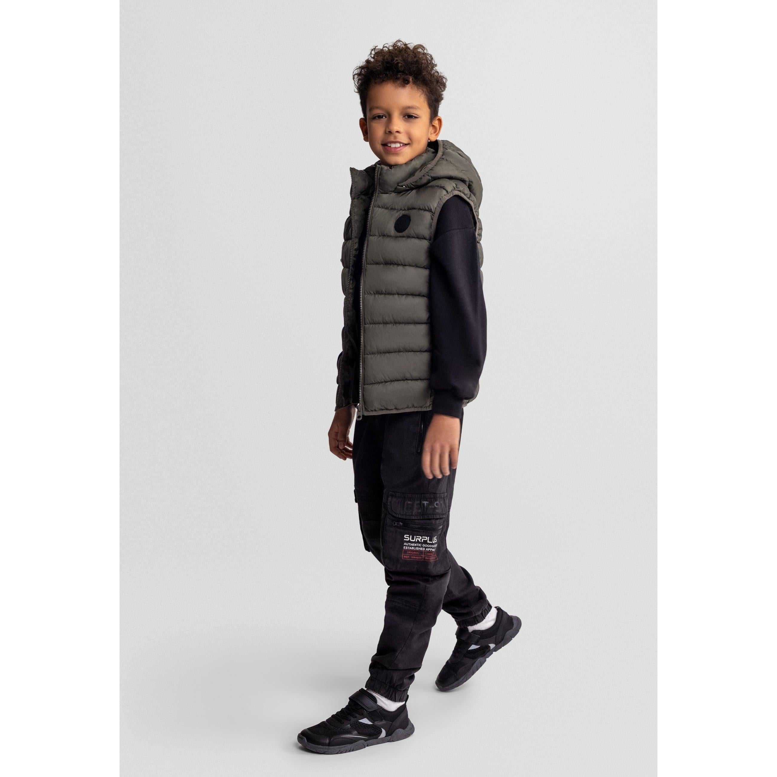 Side view of boy in khaki gilet showing detachable hood and black cargo-style trousers