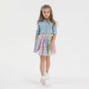 Girl in multicolor sequin tulle skirt with gold elastic waistband and layered design.