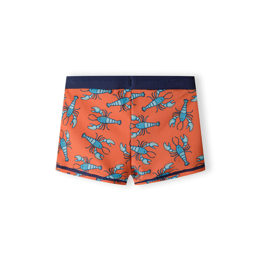 Back view of orange swim shorts with blue lobster print pattern laid flat against white background, showing navy waistband