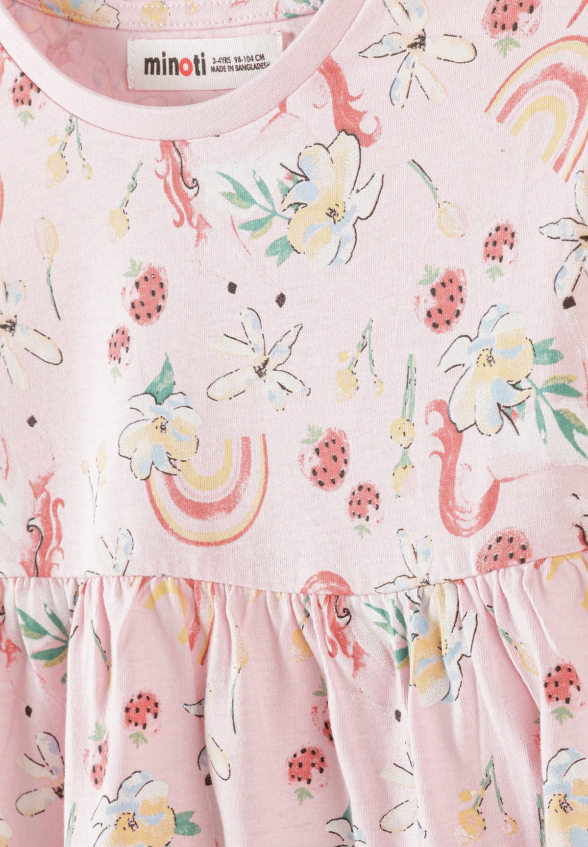 Detail shot showing Minoti label at neckline and intricate print pattern with unicorns, rainbows, strawberries and daisies on light blue fabric
