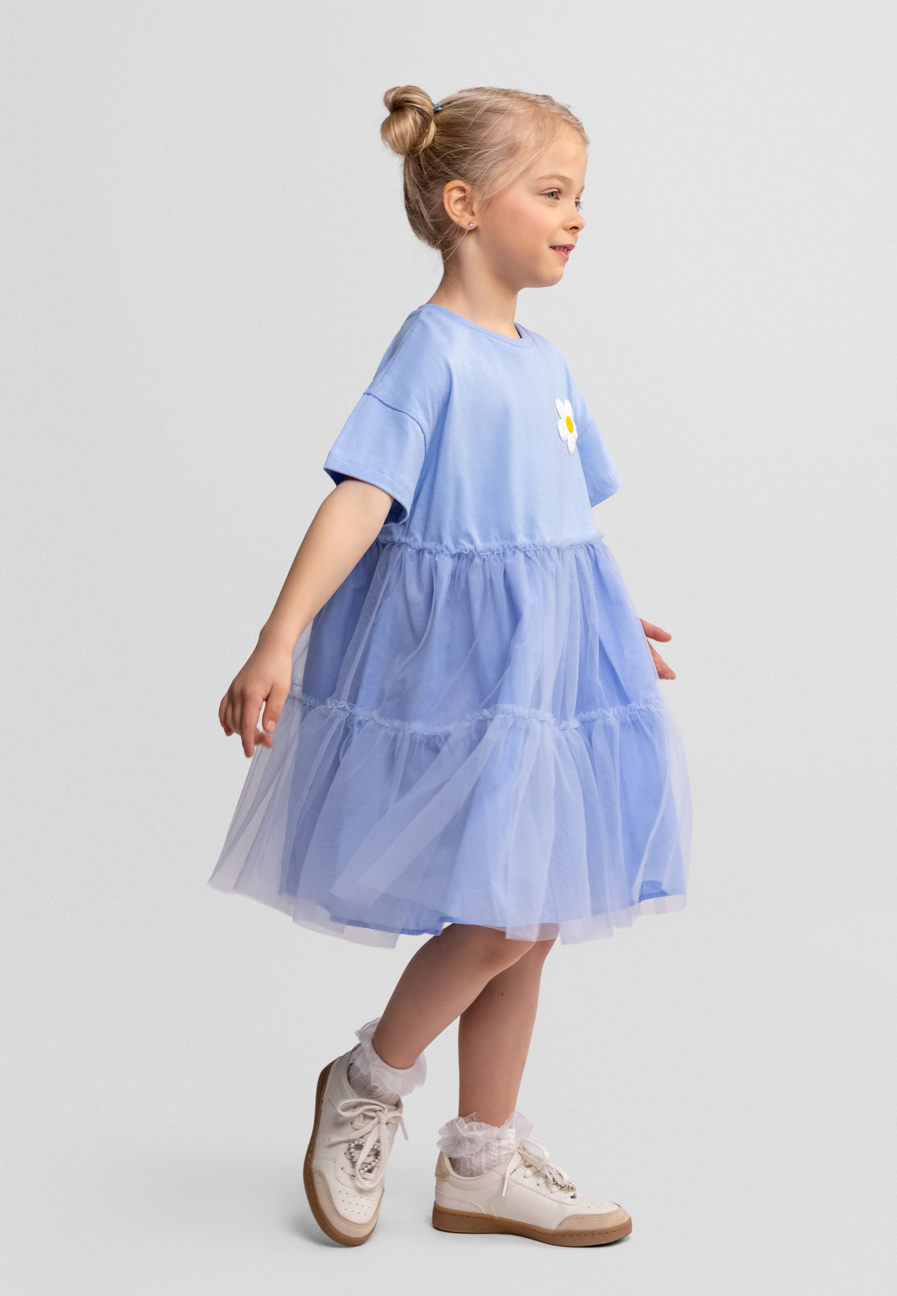 Young girl wearing a light blue dress with a plain background