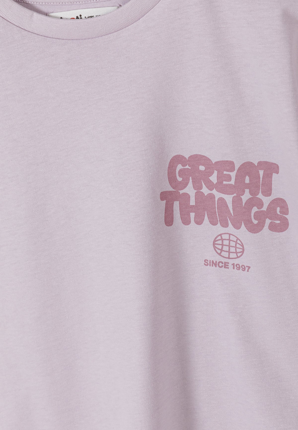 Close-up detail of charcoal t-shirt showing sunshine graphic design with sleeping sun face surrounded by radiating rays, pink text reading 'FREE SUNSHINE FREE SPIRIT' with decorative flowers and stars on grey fabric