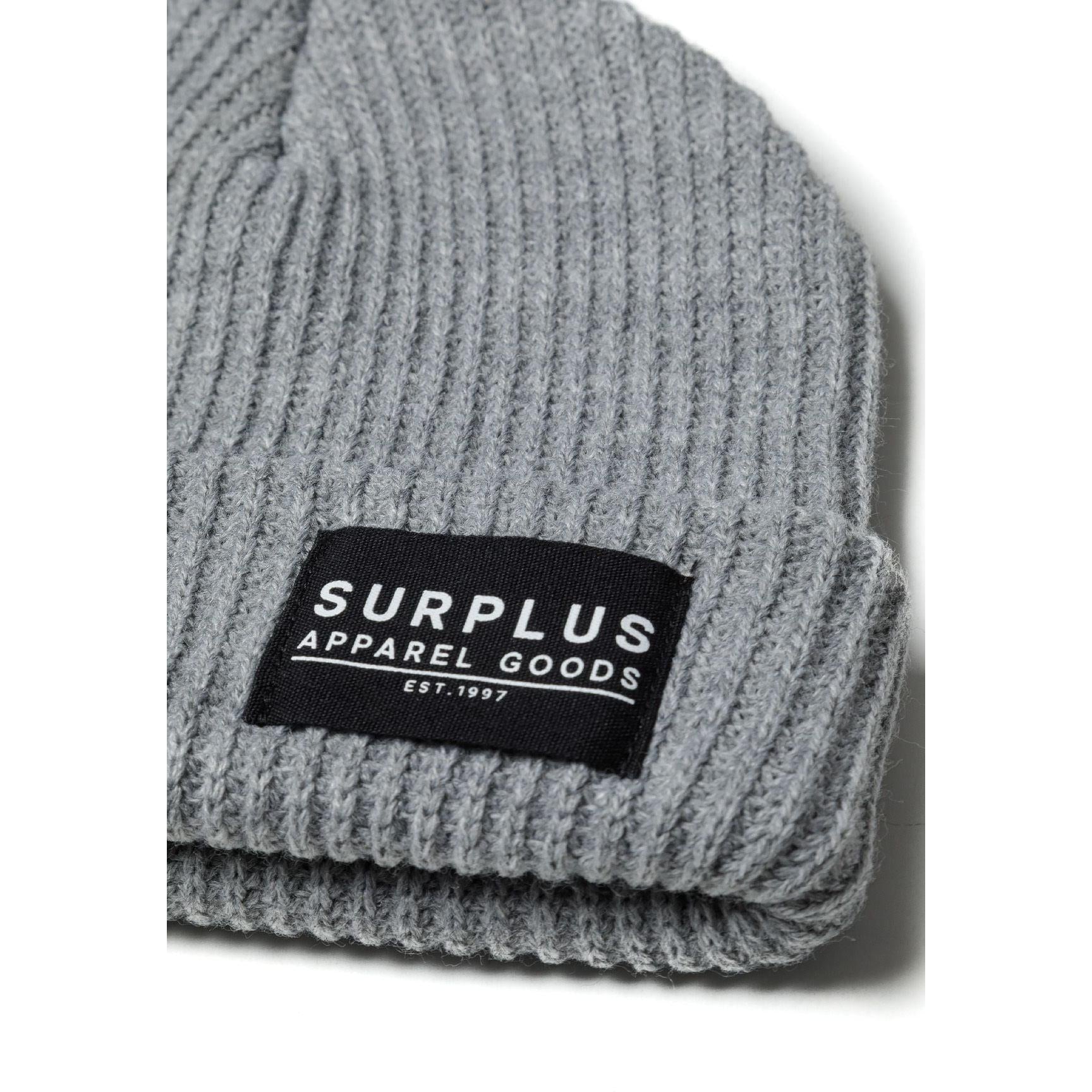 Detail shot of grey ribbed beanie showing knit texture and black Surplus Apparel Goods Est. 1997 woven label