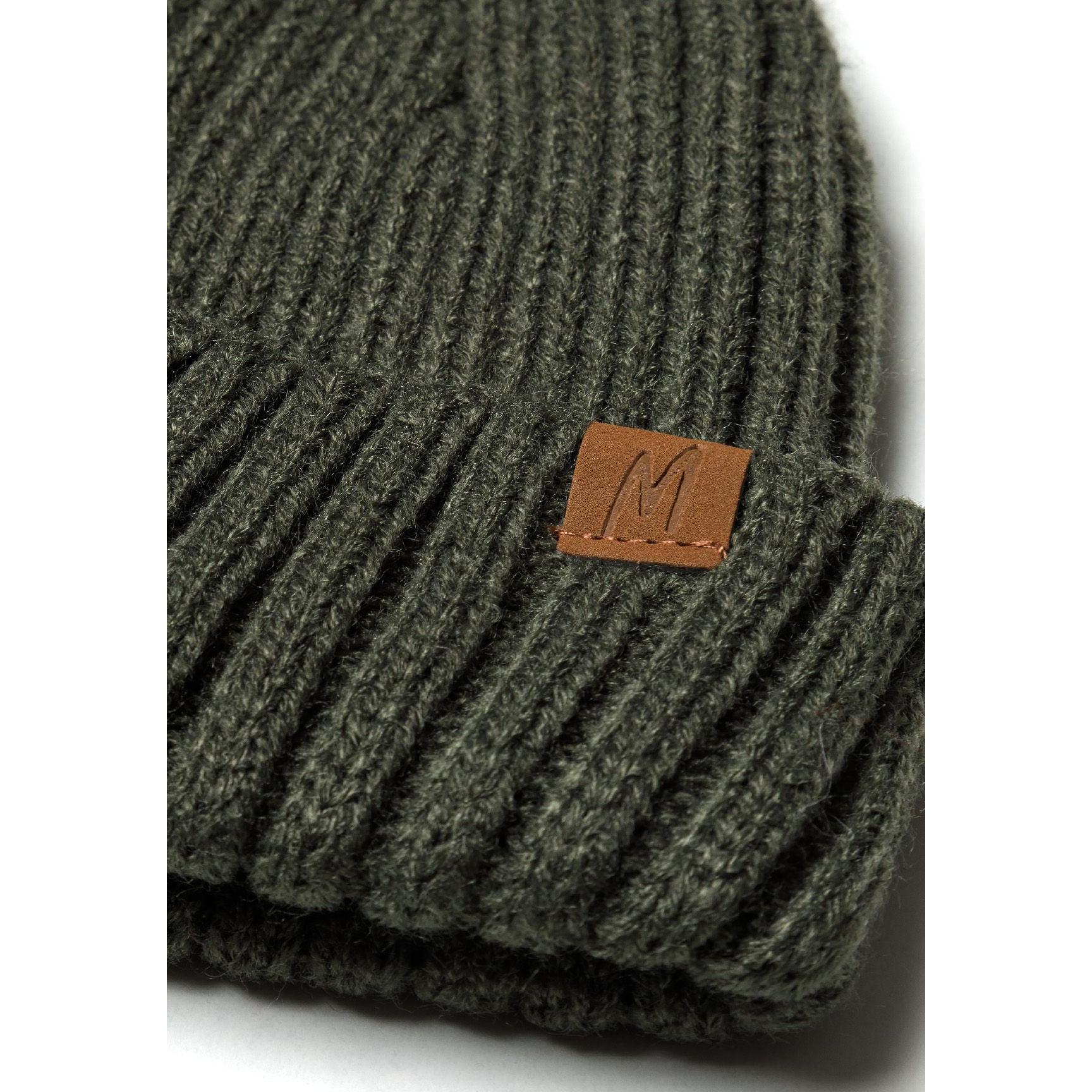 Close-up detail of khaki ribbed knit fabric showing texture and brown leather Minoti label patch