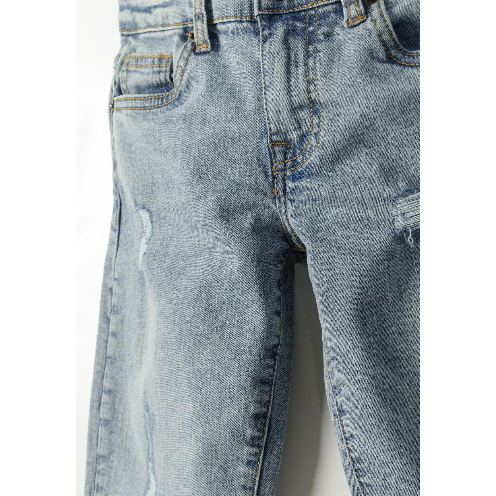 Close-up detail of light blue jeans showing distressed rips and tears on the leg area with visible denim texture and stitching