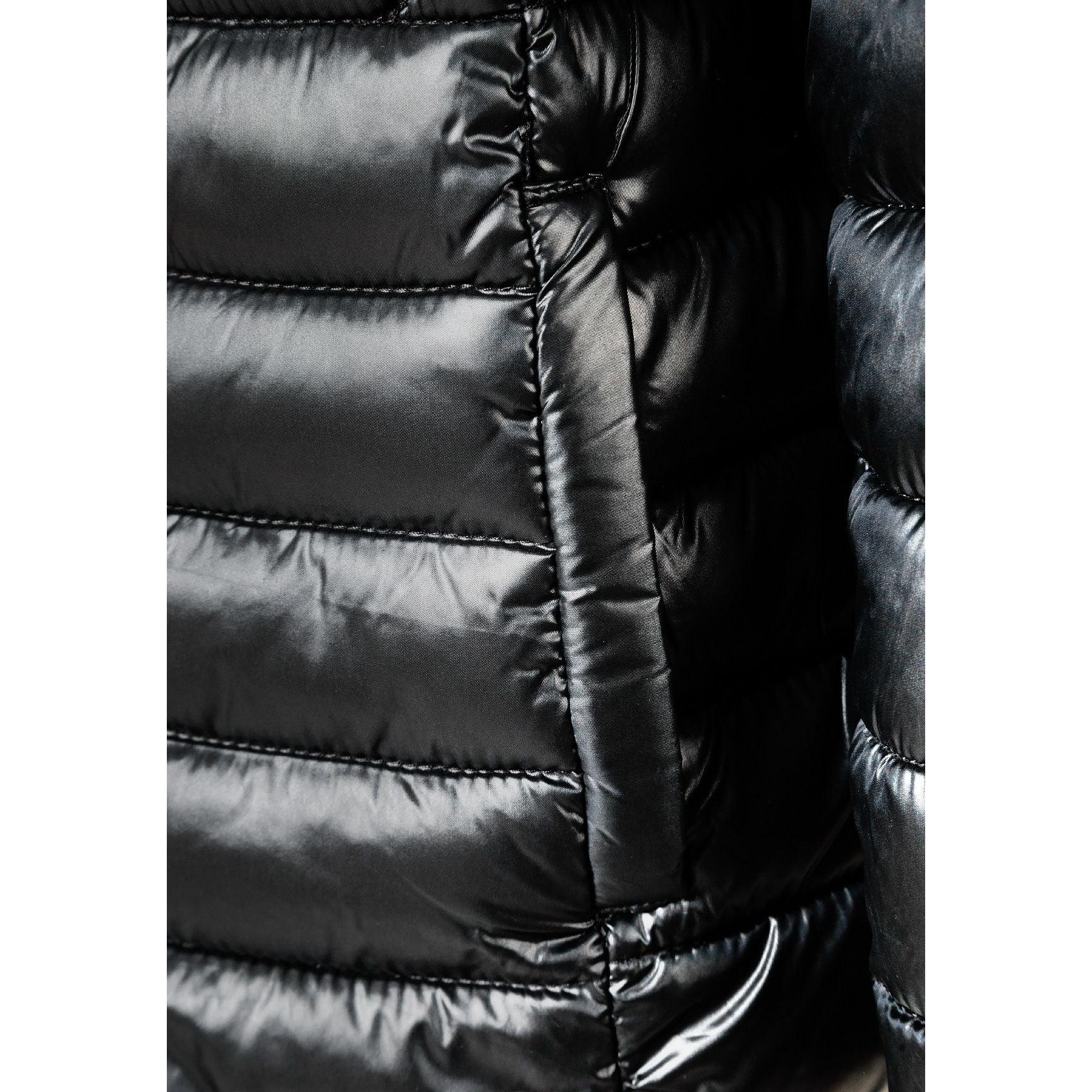 Close-up detail of circular embroidered patch on black quilted jacket sleeve featuring heart design with text around border