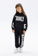 Girls hooded tracksuit in black, featuring printed details, front view.