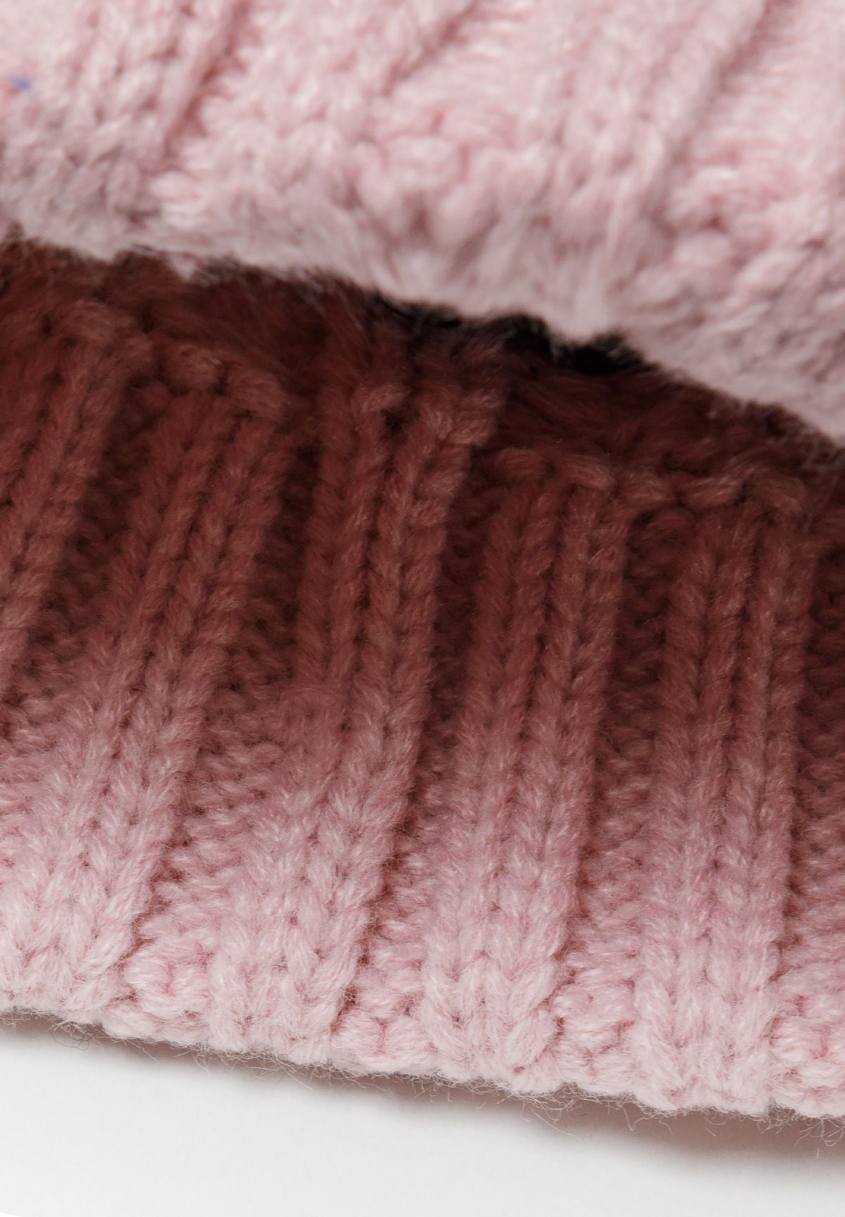 Light pink cable-knit bobble hat, inside turn-up.